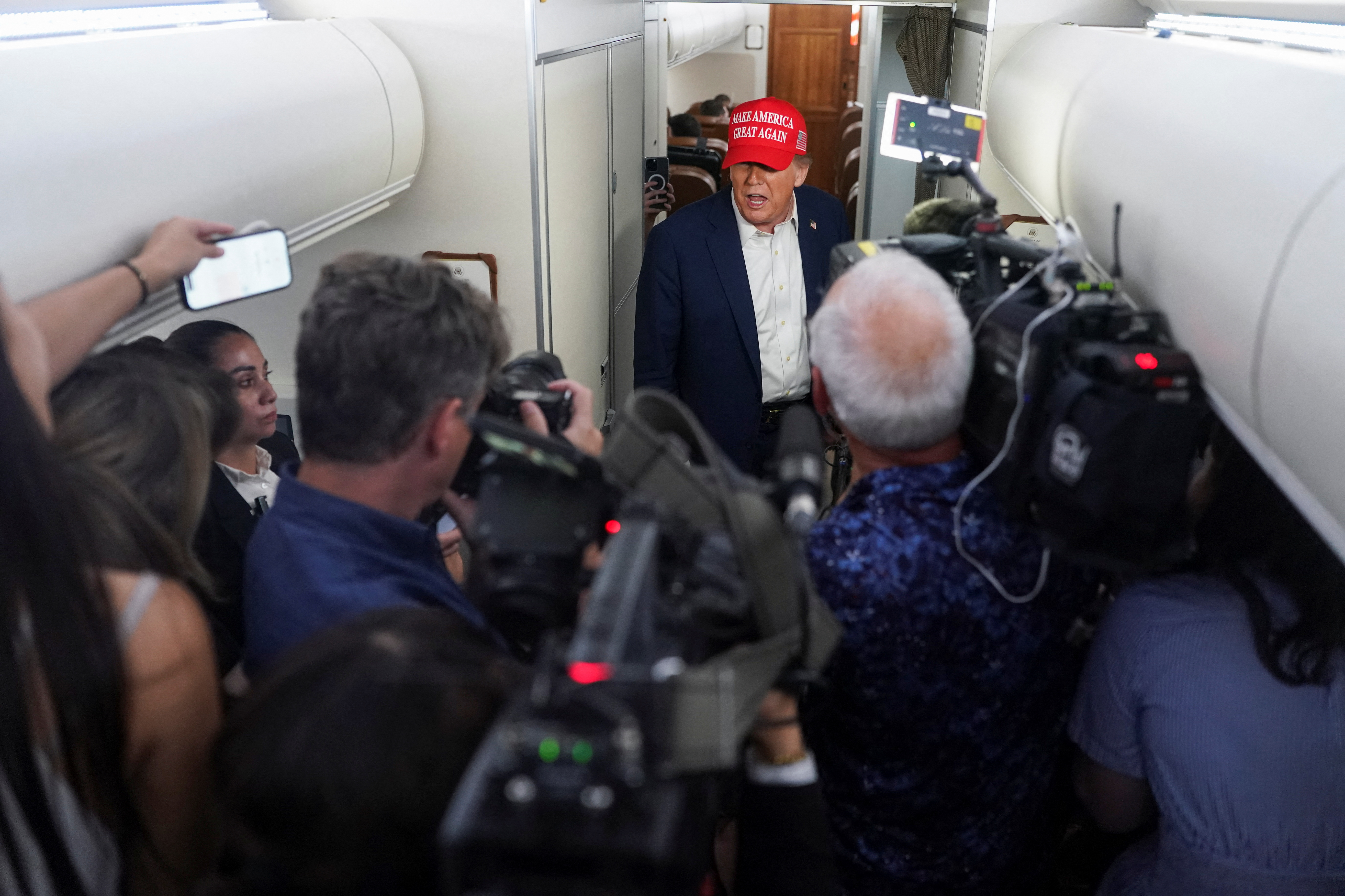 U.S. President Donald Trump speaks to members of the media on board Air Force One on the way to New Jersey