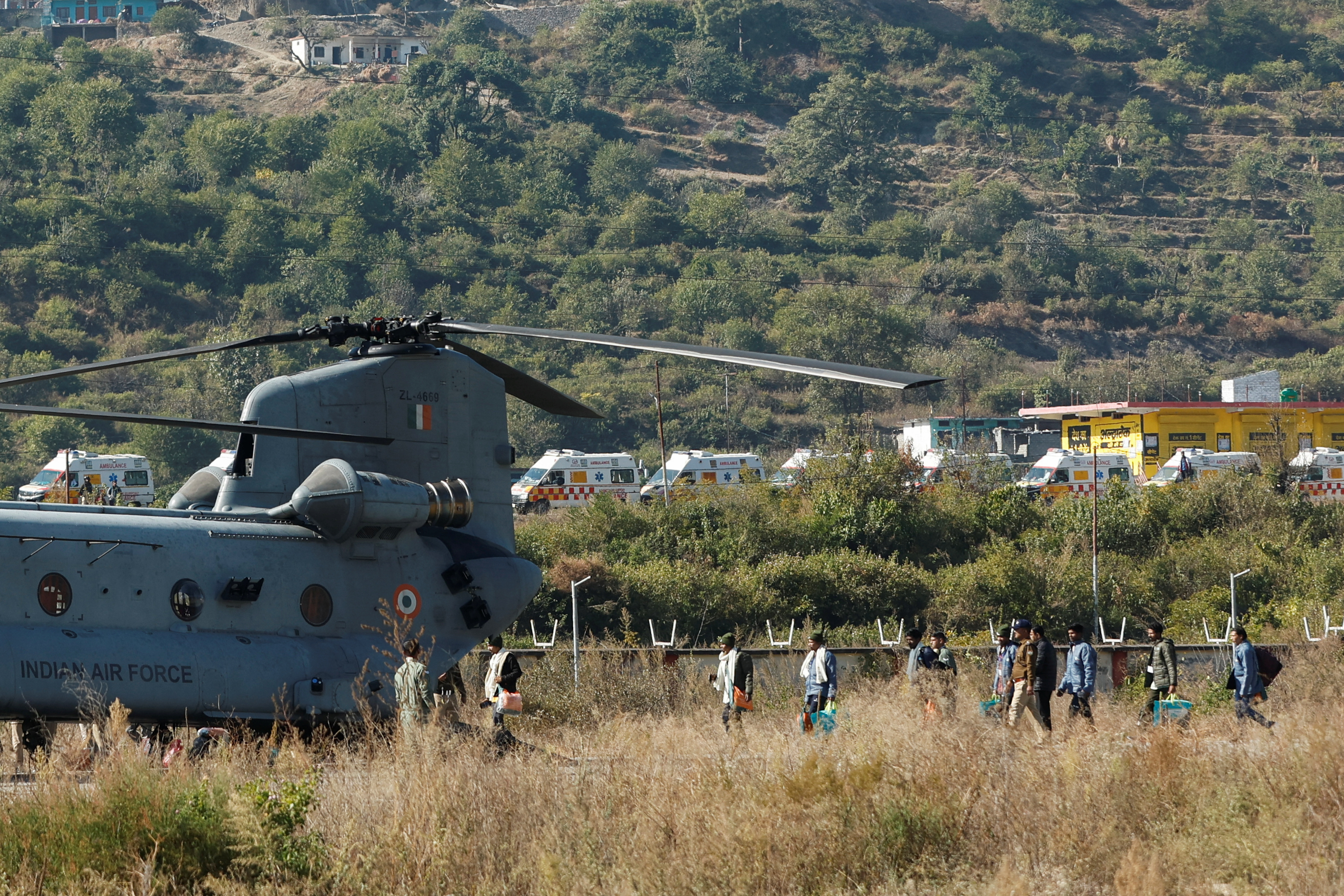 Workers, who were rescued from a tunnel which collapsed in Uttarkashi, walk to board an Indian Air Force's Chinook helicopter to be airlifted to AIIMS Rishikesh hospital, in Chinyalisaur