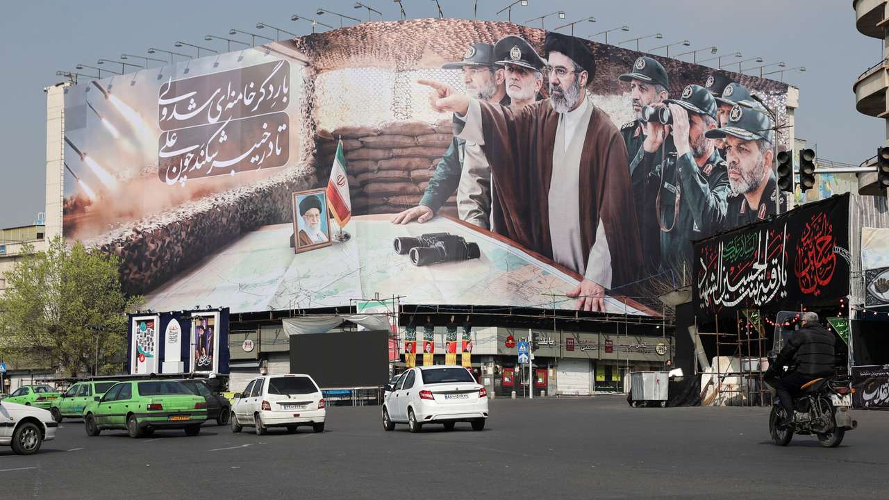 Cars pass a banner featuring Iran's new Supreme Leader Mojtaba Khamenei, in Tehran