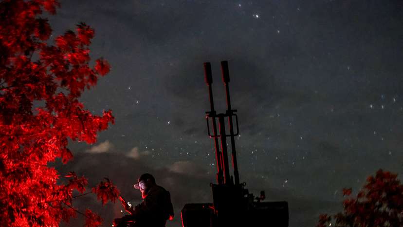 FILE PHOTO: A Ukrainian serviceman from an anti-drone mobile air defence unit uses his mobile device near an anti aircraft cannon as he waits for Russian kamikaze drones in Kherson region
