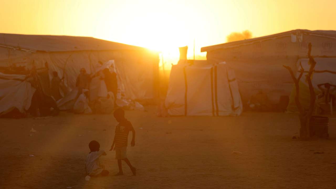Sudanese refugee children from al-Fashir play during the sunset over the Tine transit refugee camp