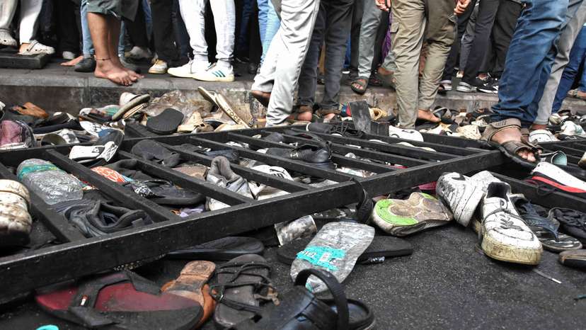 People walk past shoes left behind following a stampede outside a cricket stadium in Bengaluru