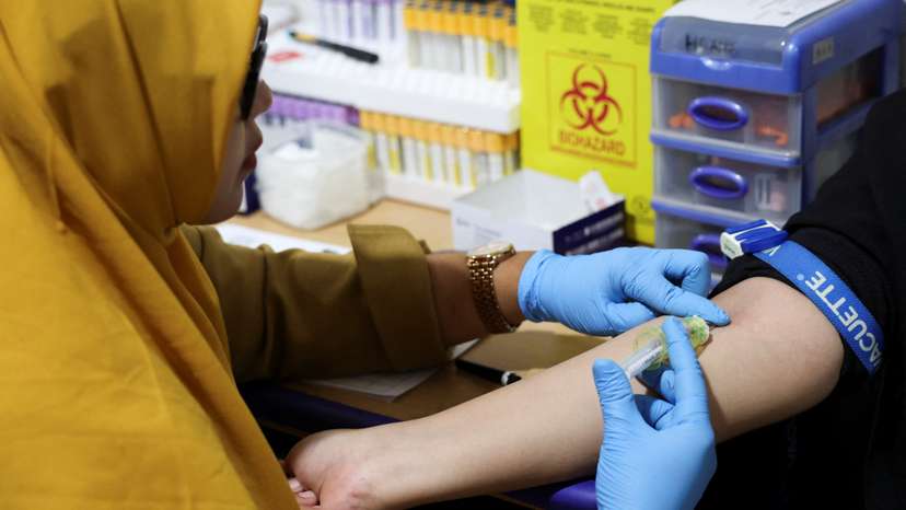 A staff member takes a blood sample during a free medical check-up for the public at the government-run healthcare center in Jakarta