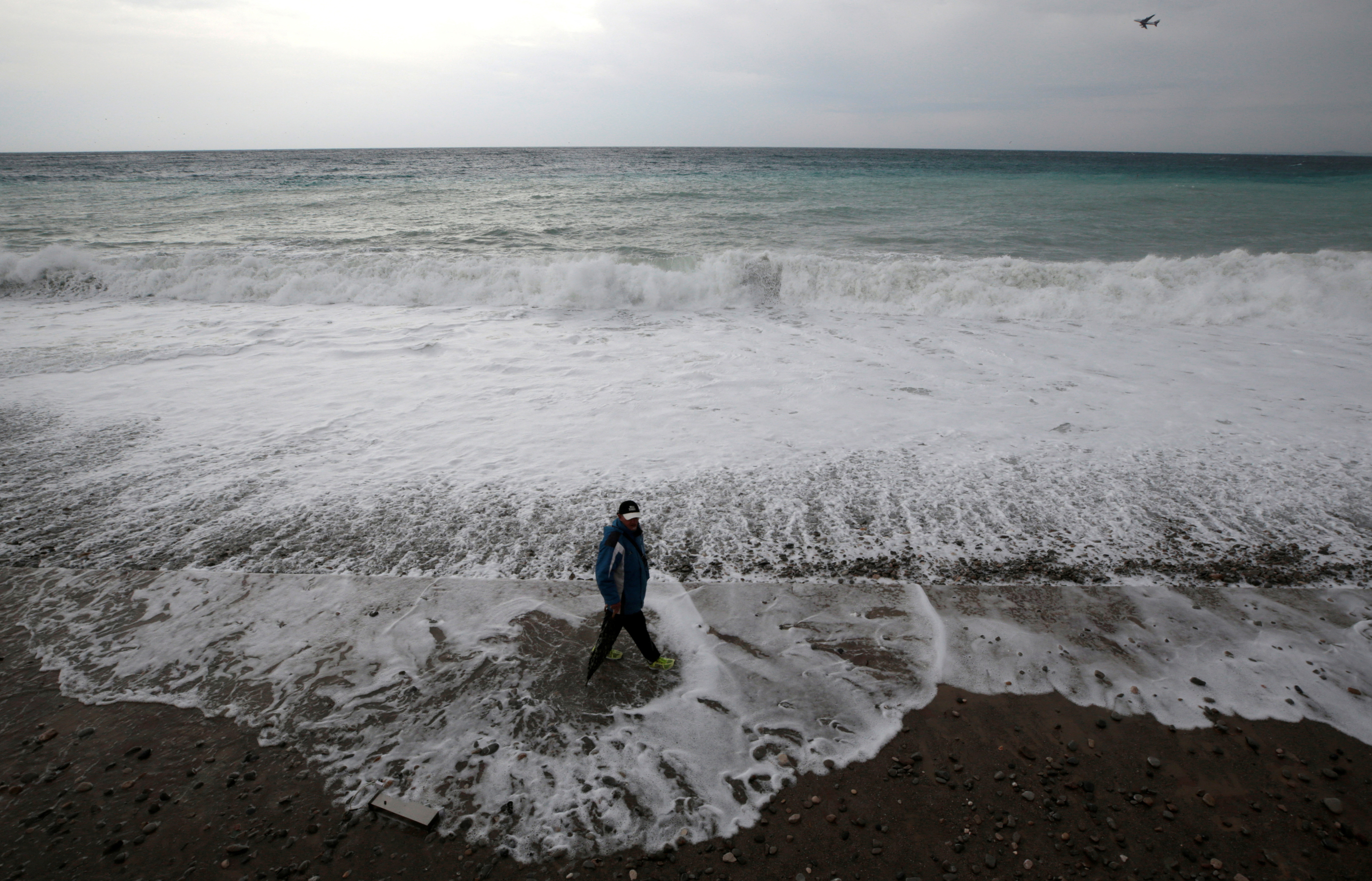 FILE PHOTO: A man walks on the beach in Nice as storms and heavy rain lashed through southern France
