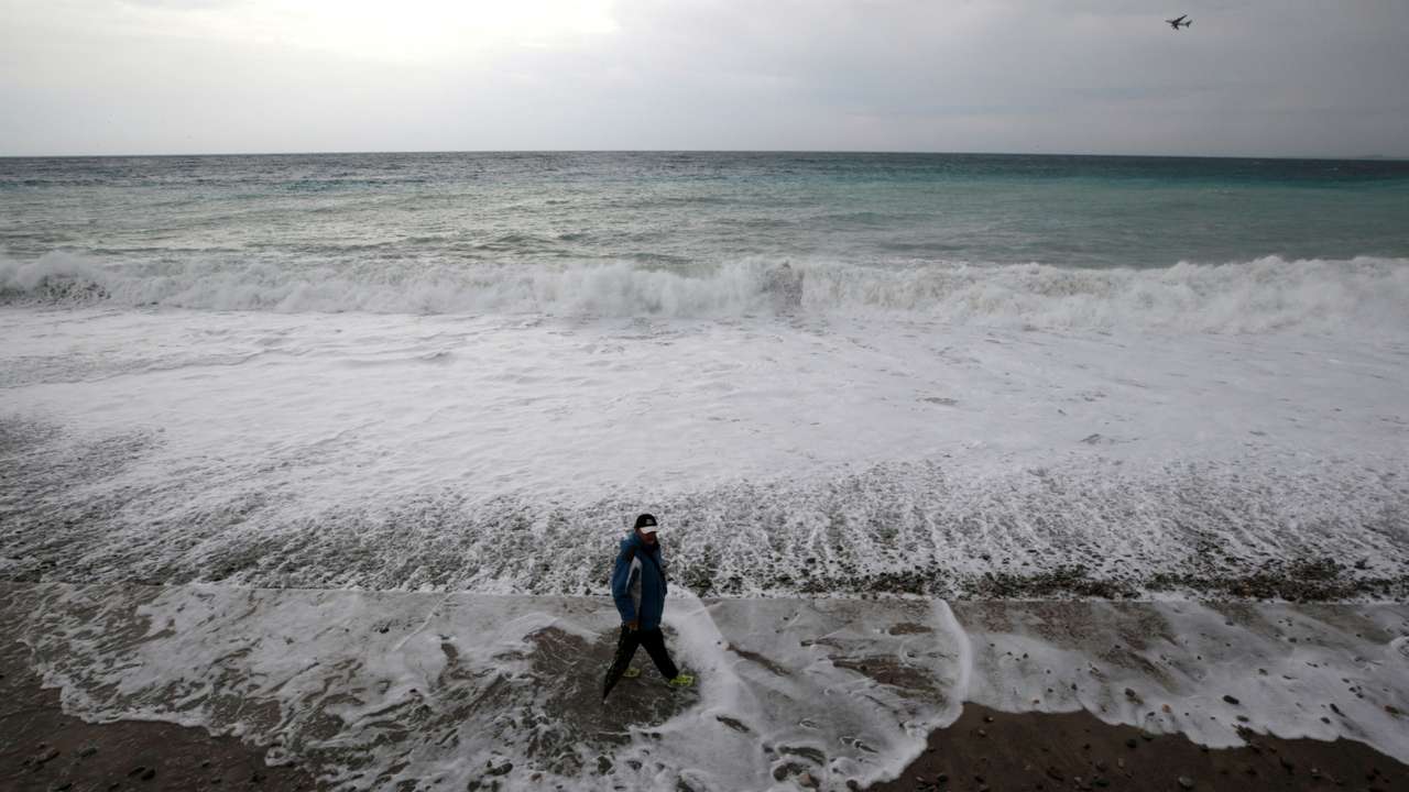 FILE PHOTO: A man walks on the beach in Nice as storms and heavy rain lashed through southern France