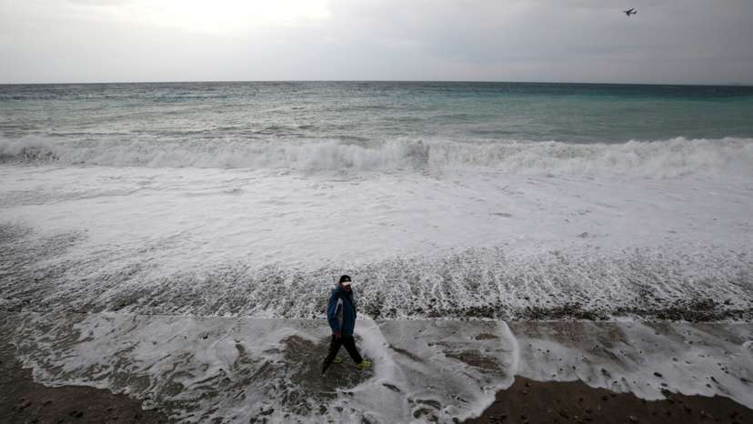 FILE PHOTO: A man walks on the beach in Nice as storms and heavy rain lashed through southern France