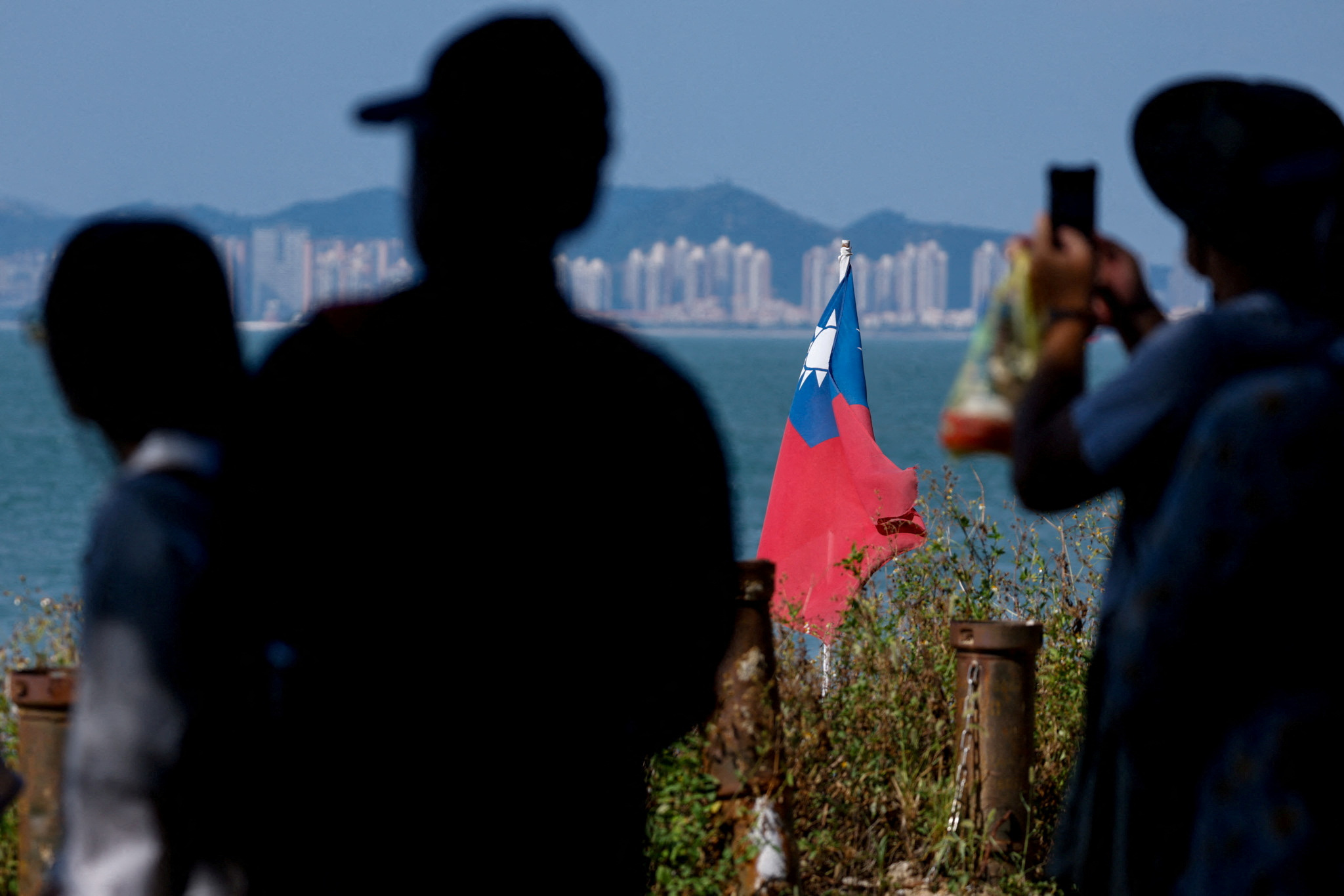 FILE PHOTO: Tourists take photos as a Taiwan flag flies, with China's Xiamen in the background, on Dadan Island