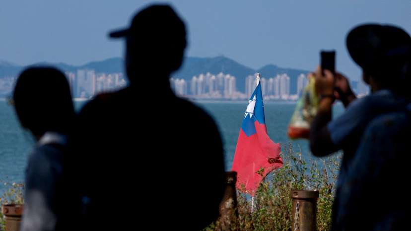 FILE PHOTO: Tourists take photos as a Taiwan flag flies, with China's Xiamen in the background, on Dadan Island