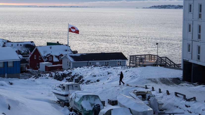 A Greenland flag flies as a man walks on the day of the meeting between top U.S. officials and the foreign ministers of Denmark and Greenland, in Nuuk