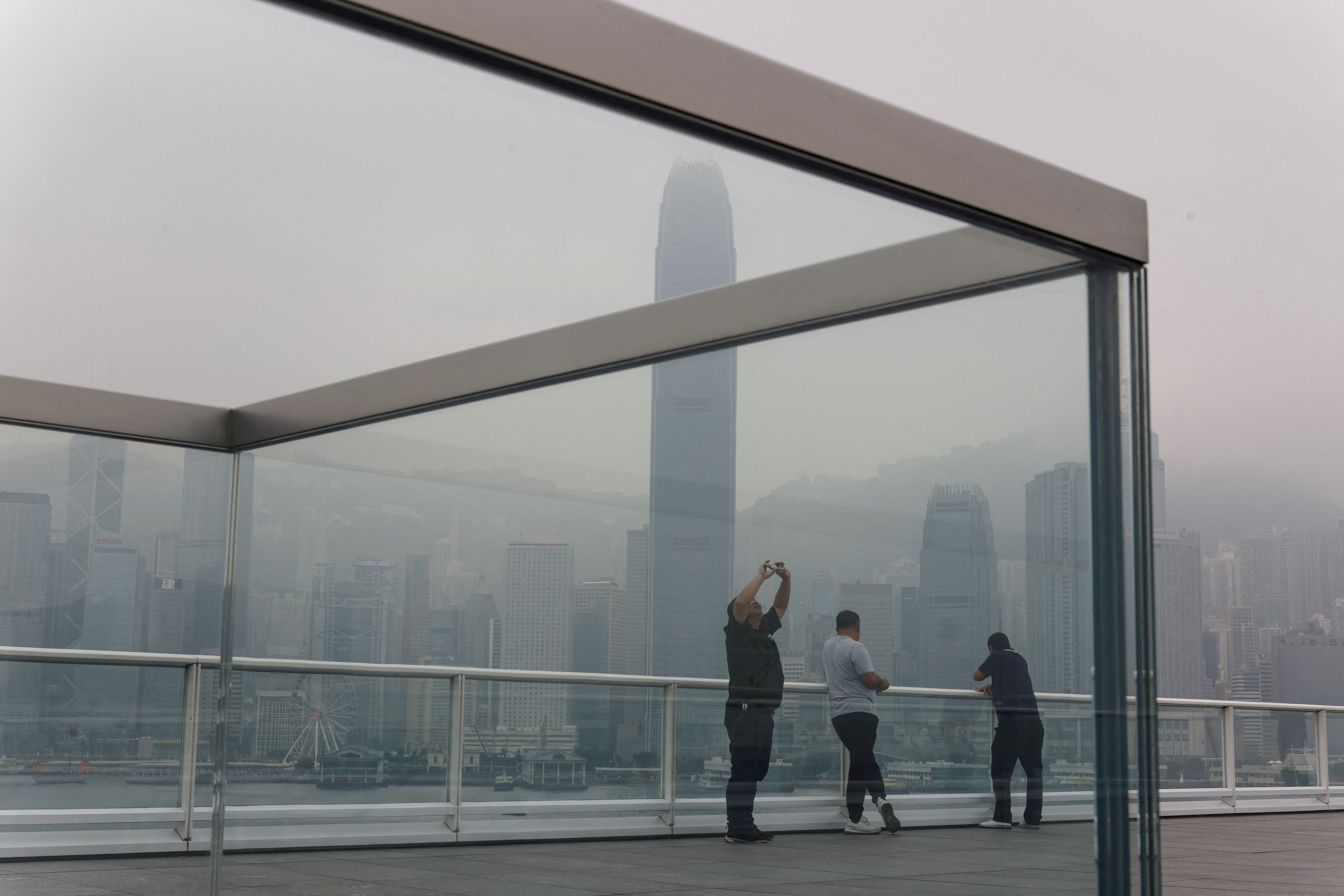 People take photos at the waterfront during a foggy day in Hong Kong