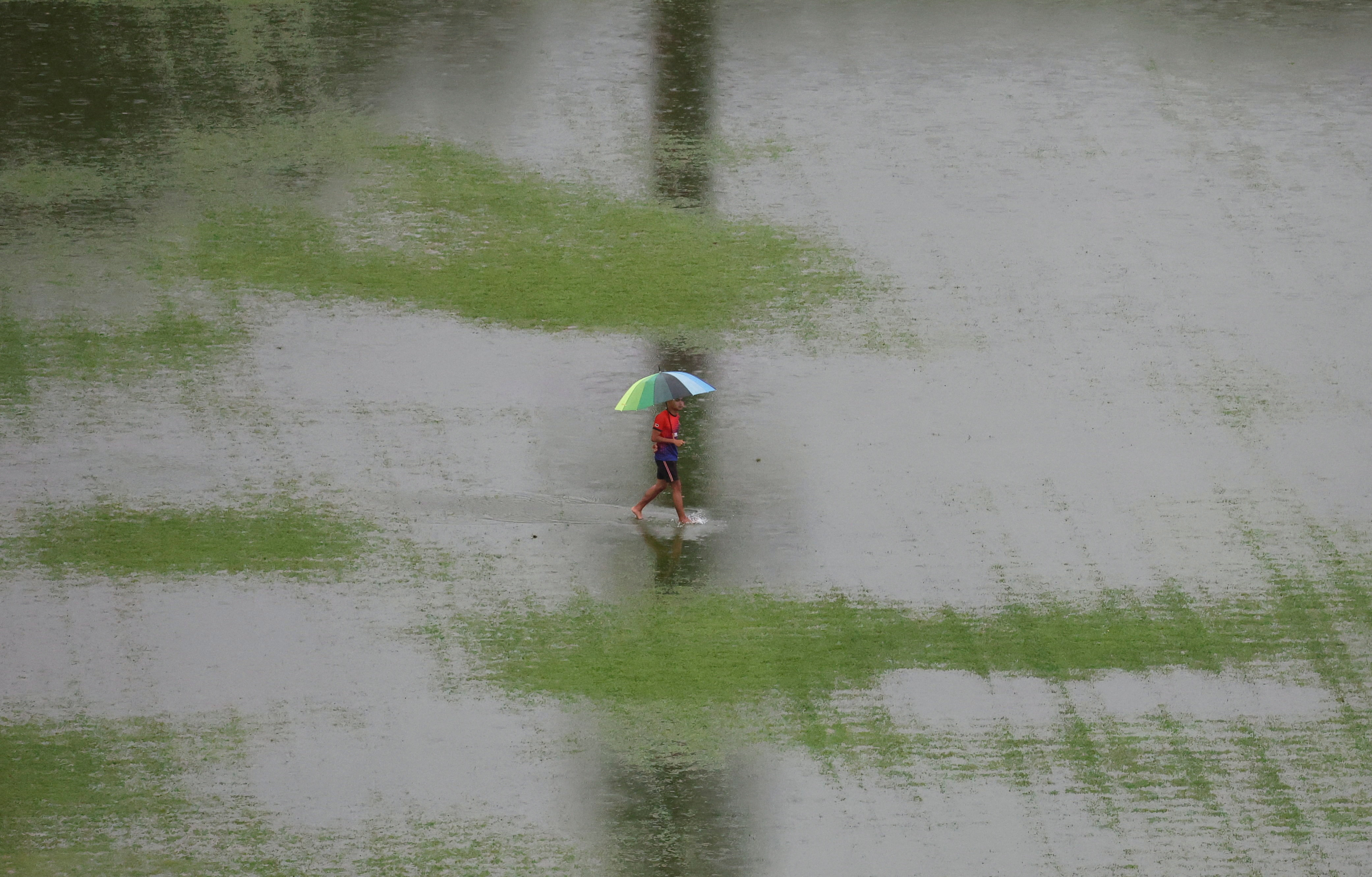 A man walks through floodwater as rain pours in Kuala Lumpur