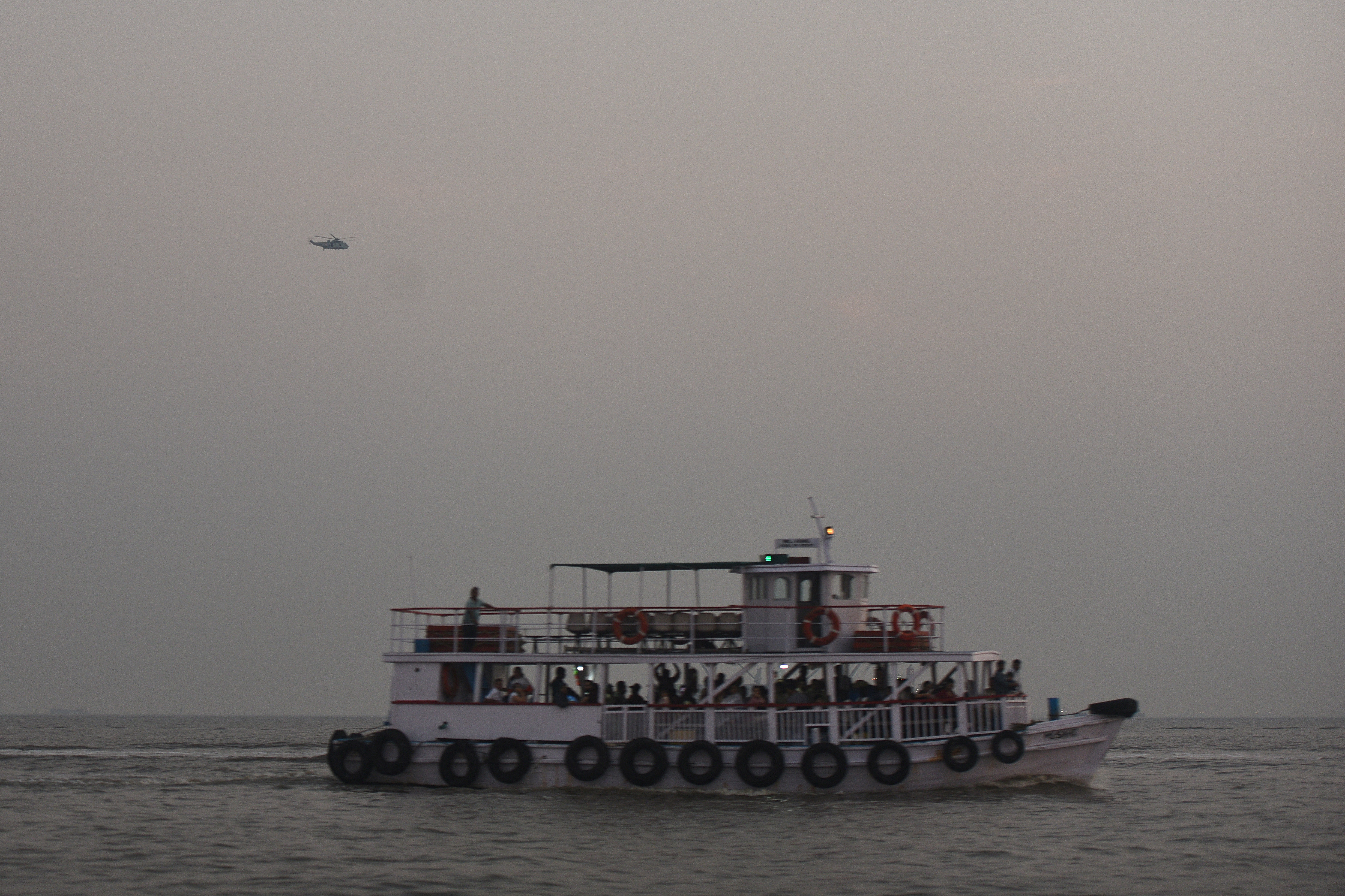 A military helicopter flies over a ferry during a rescue operation after a passenger boat capsized off the coast of India's financial capital Mumbai