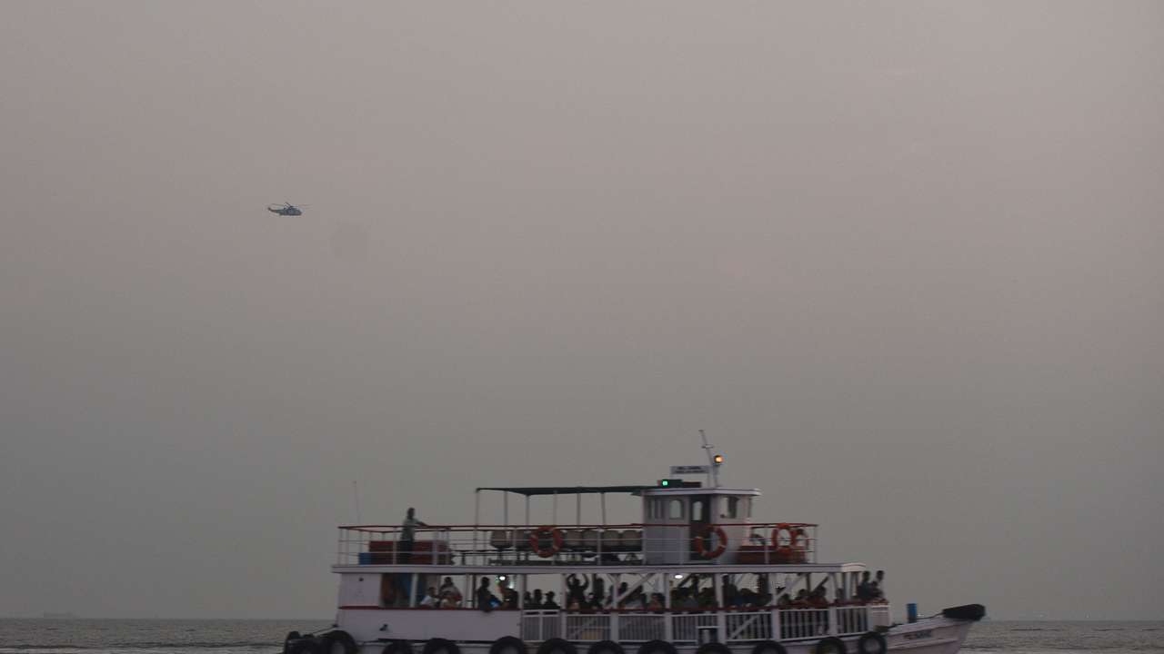 A military helicopter flies over a ferry during a rescue operation after a passenger boat capsized off the coast of India's financial capital Mumbai