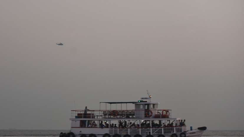 A military helicopter flies over a ferry during a rescue operation after a passenger boat capsized off the coast of India's financial capital Mumbai