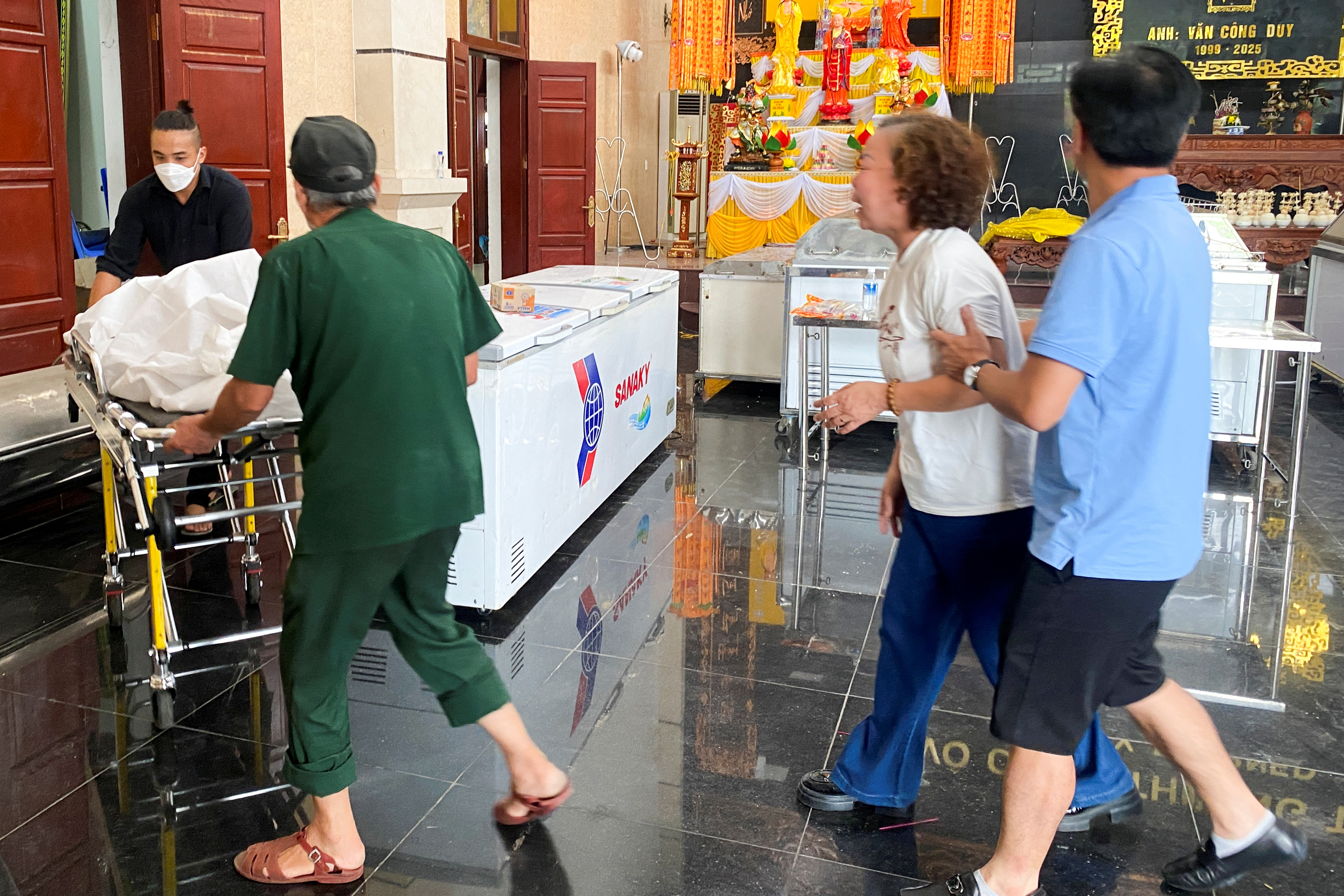 Nguyen Thi Lien, mother of Tran Trung Tuan, reacts as hospital staff carry his body, at Bai Chay Hospital, in Quang Ninh province