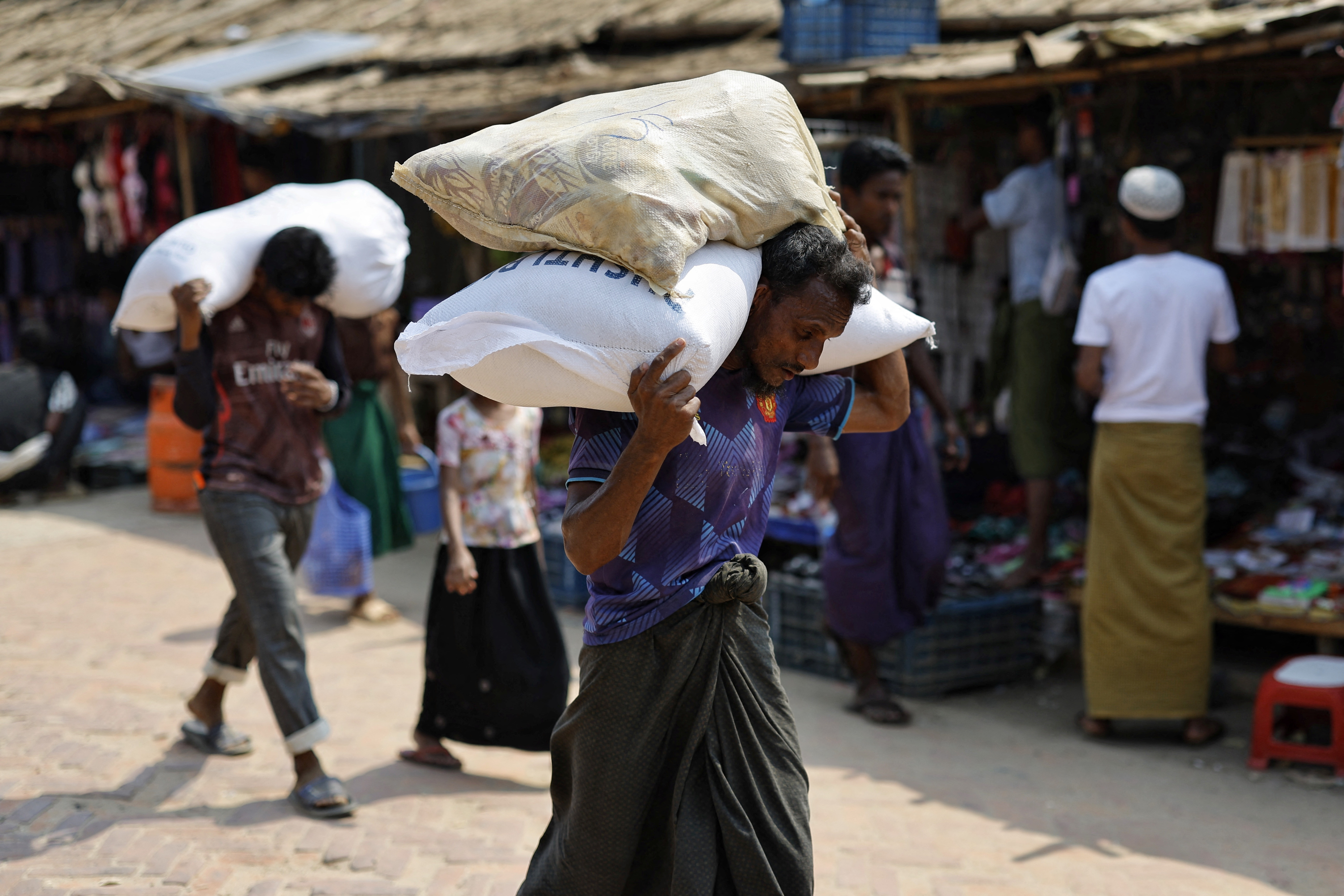 Rohingya refugees carry relief supplies after receiving them from a distribution centre at a refugee camp in Cox's Bazar