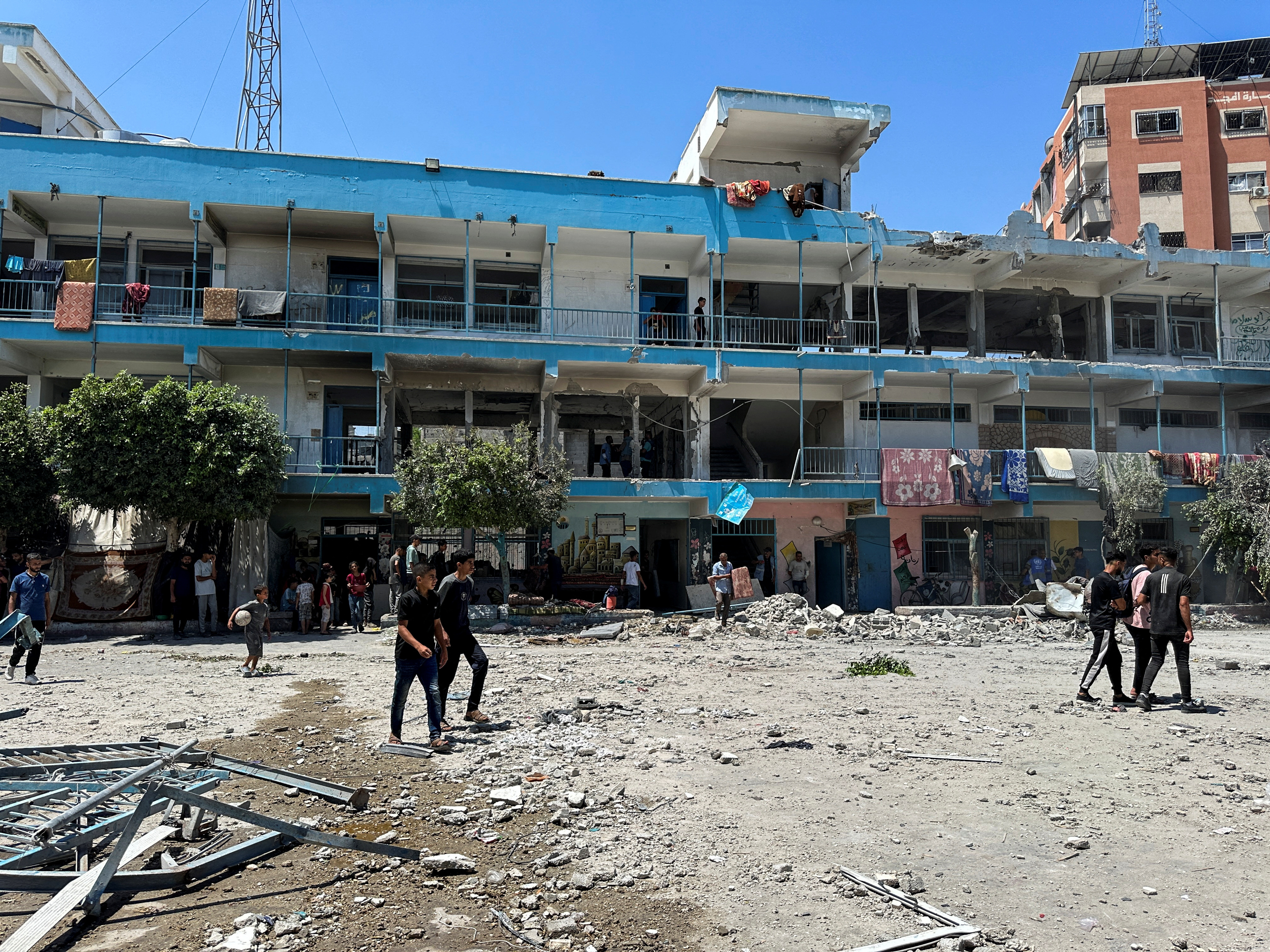 Palestinians inspect the site of an Israeli strike on a UNRWA school sheltering displaced people, in Nuseirat refugee camp