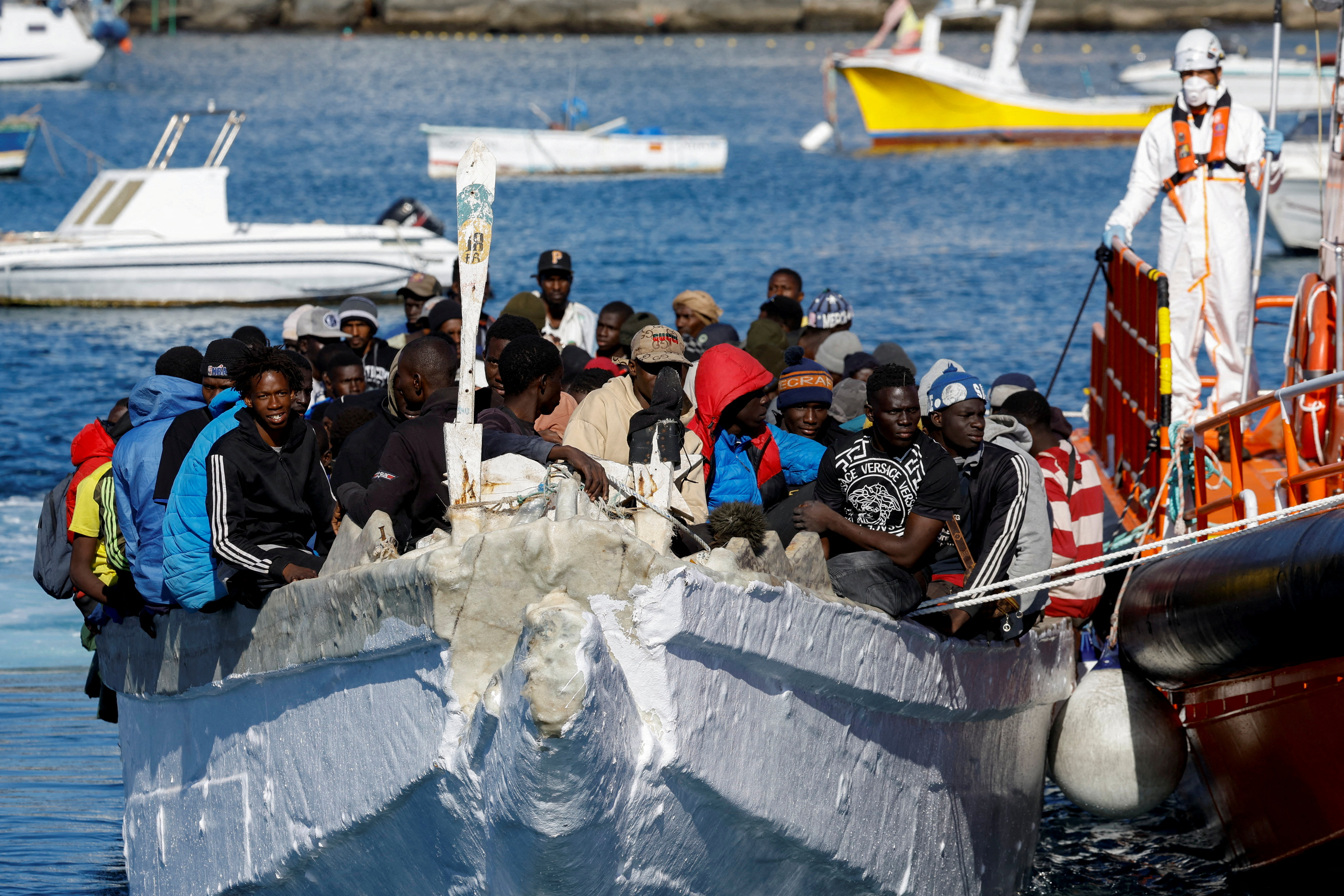 FILE PHOTO: A group of migrants wait to disembark from a wooden boat after being rescued by a Spanish coast guard vessel in the port of Arguineguin