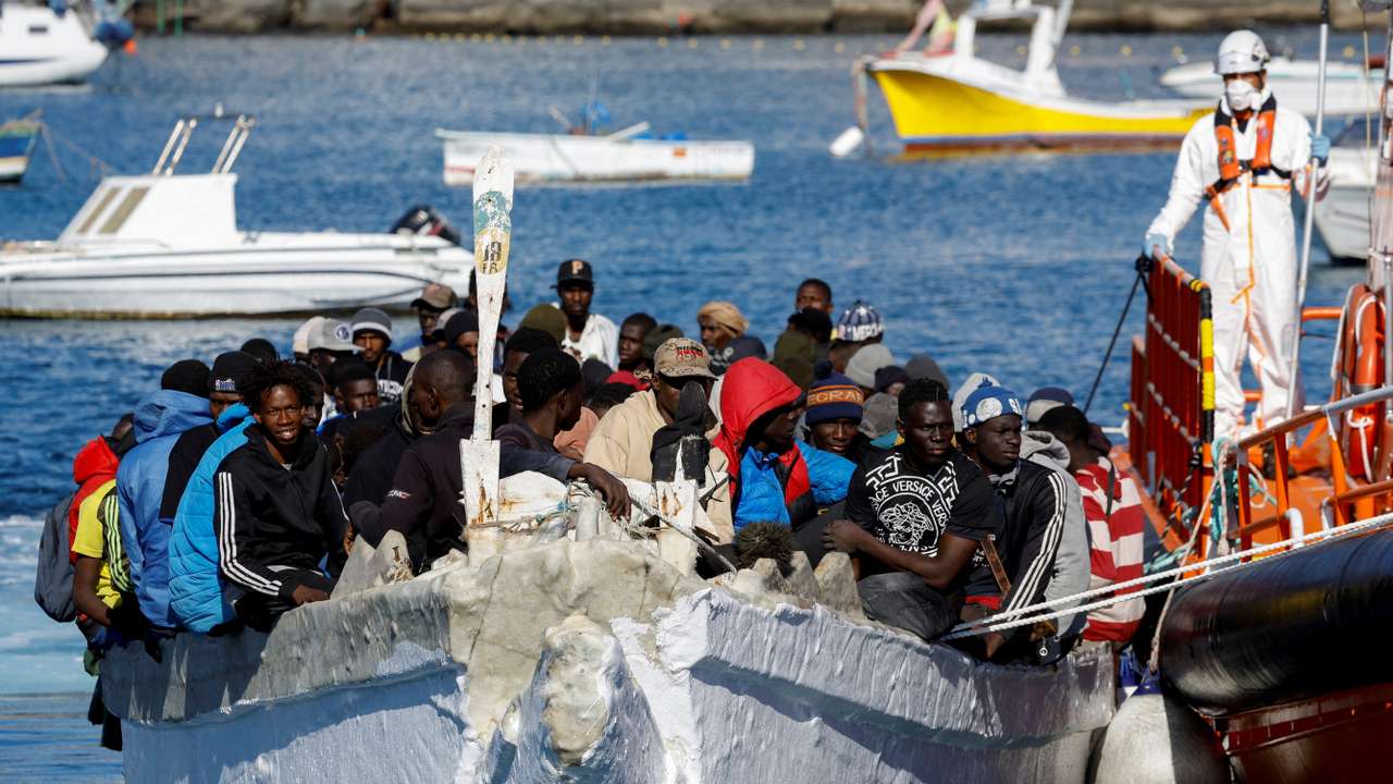 FILE PHOTO: A group of migrants wait to disembark from a wooden boat after being rescued by a Spanish coast guard vessel in the port of Arguineguin