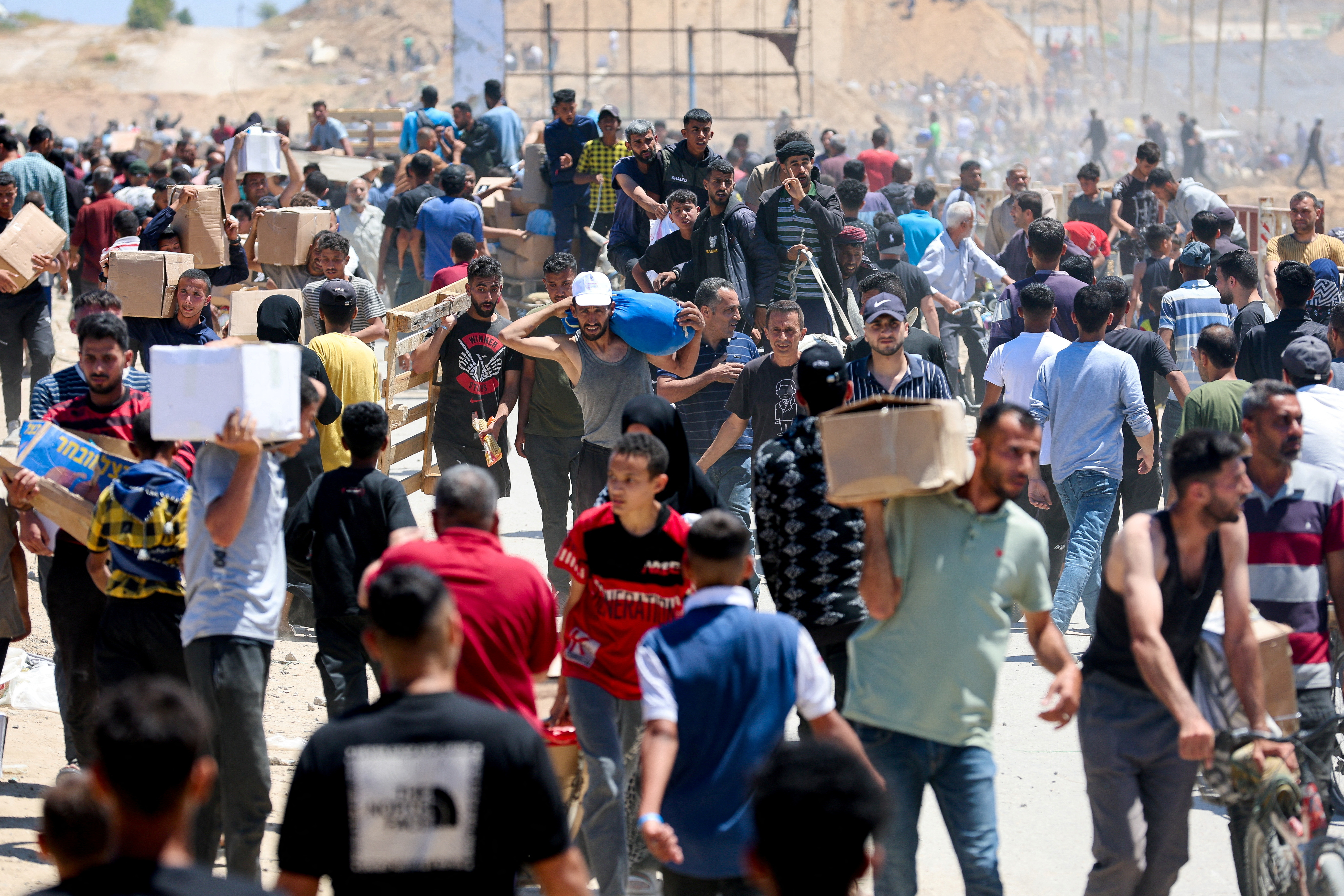 Palestinians carry aid supplies which they received from the U.S.-backed Gaza Humanitarian Foundation