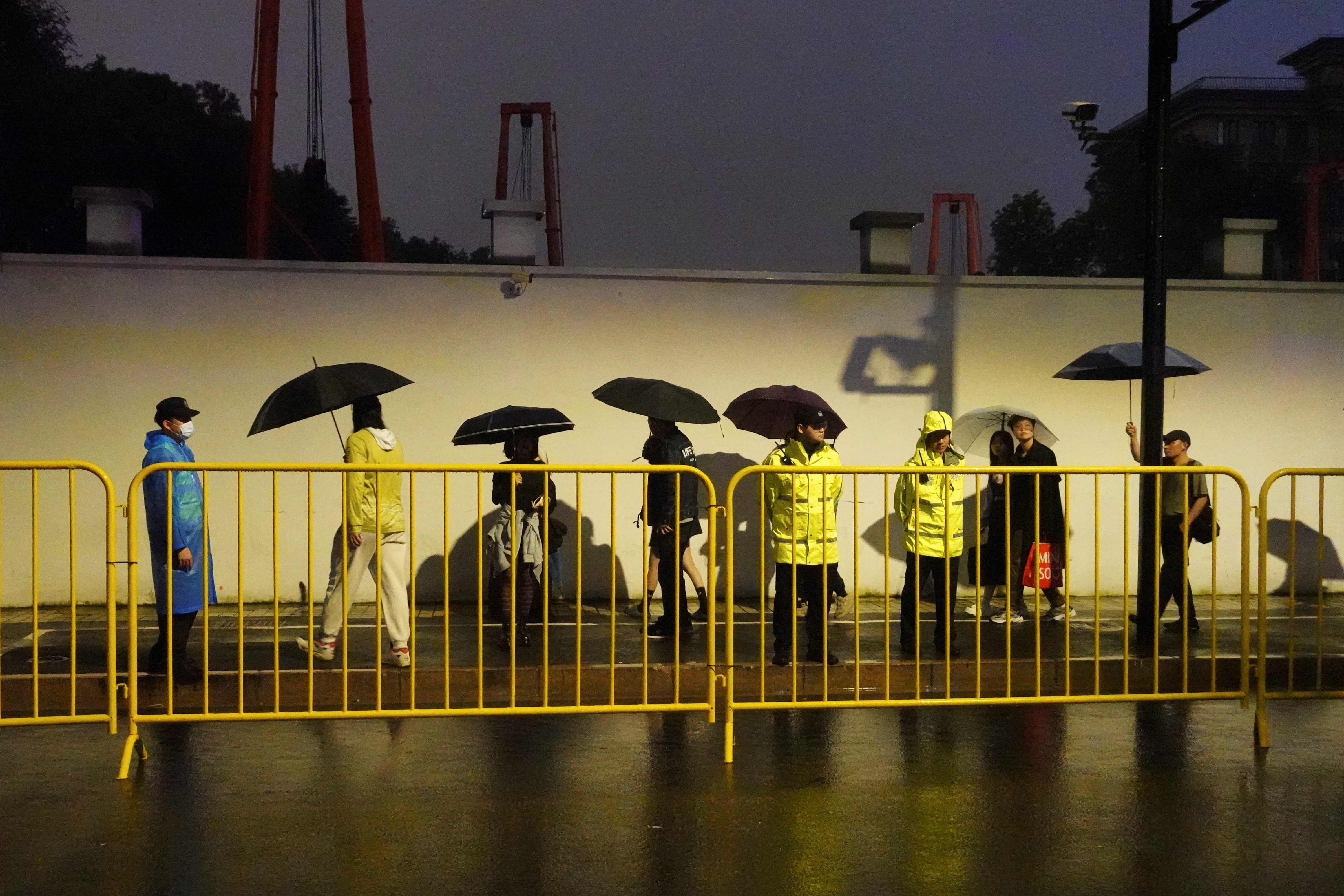 Police officers keep watch near barricades set up along a road in Shanghai