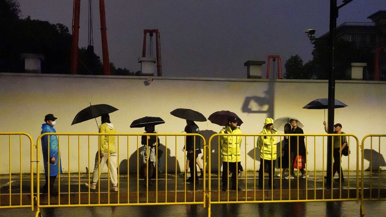 Police officers keep watch near barricades set up along a road in Shanghai