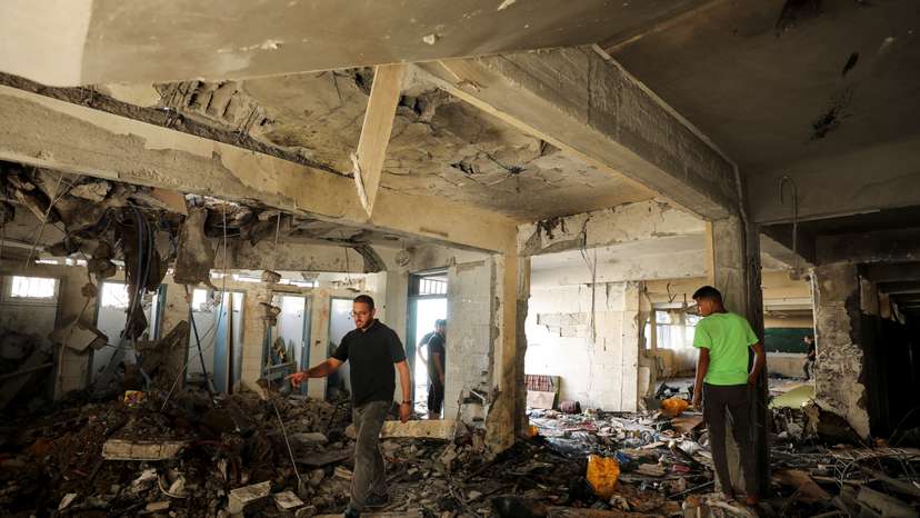 Palestinians inspect a school after it was hit by an Israeli strike, in Gaza City