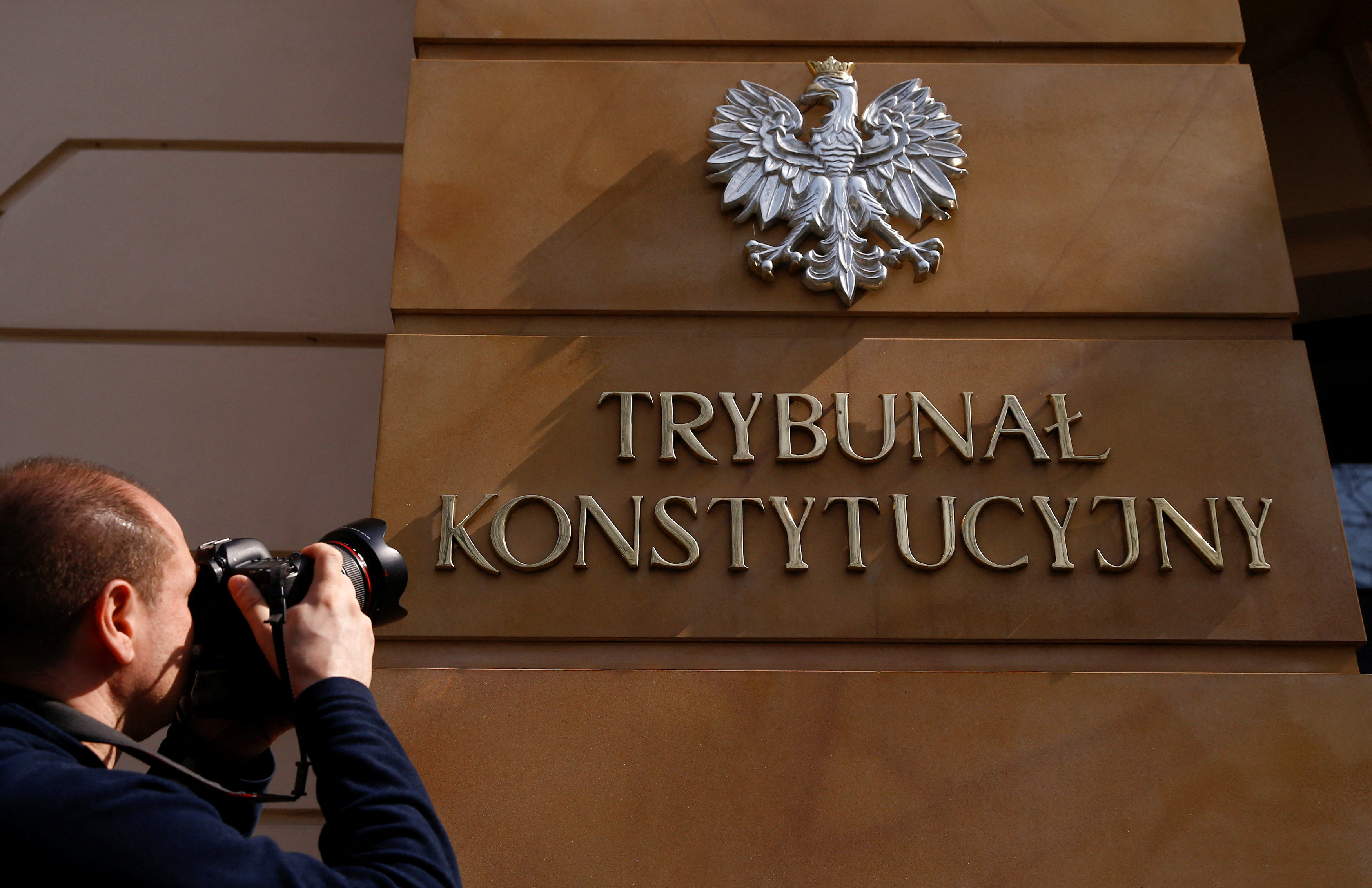 FILE PHOTO: A photographer takes a picture of the sign at the entrance to Poland's constitutional court in Warsaw