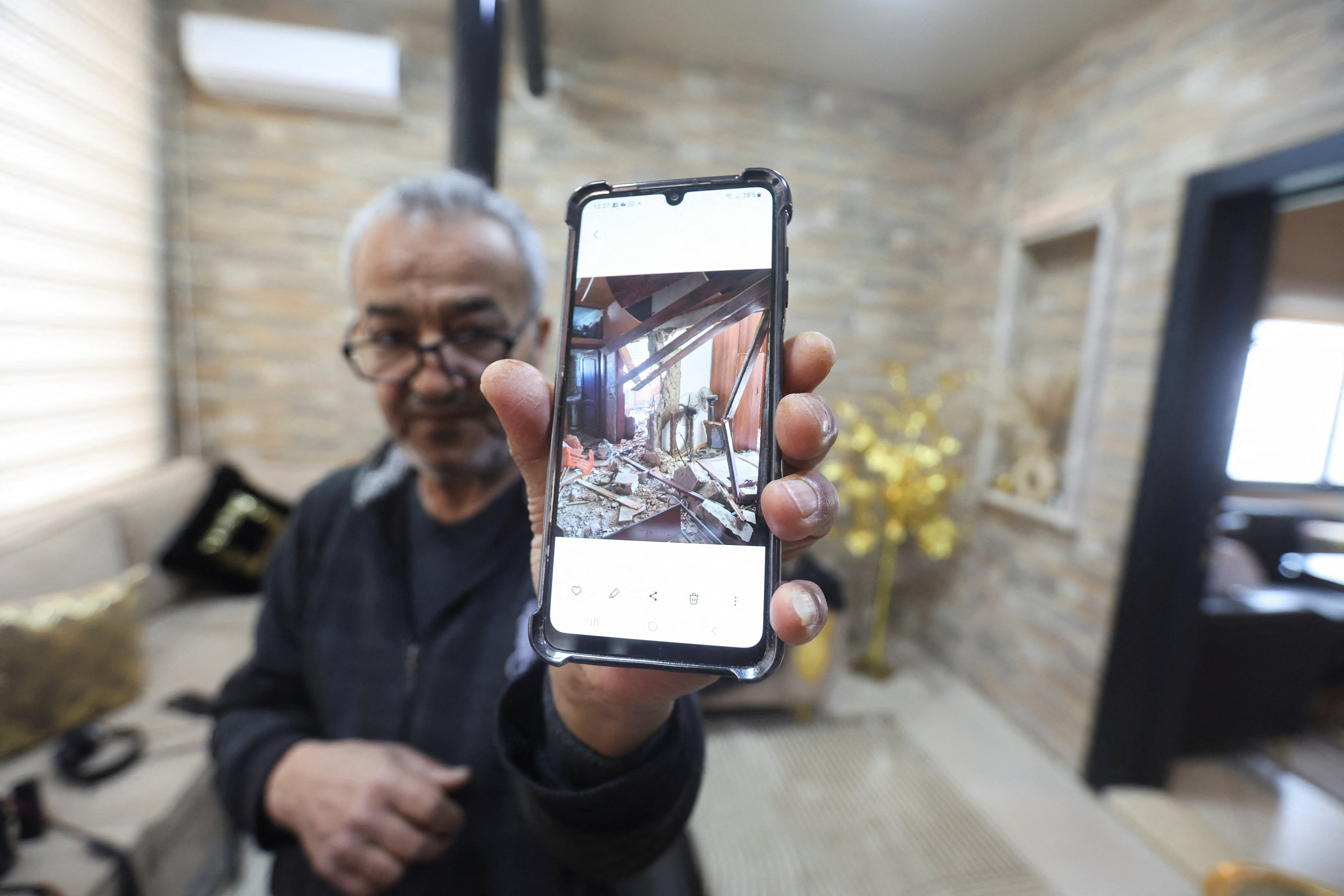 Hussain Khrais shows a picture on his phone of his home before it was rebuilt after being damaged during the latest hostilities between Israel and Lebanon, in Khiam