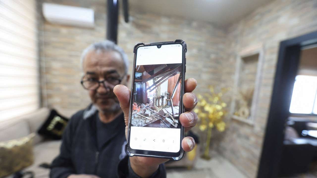 Hussain Khrais shows a picture on his phone of his home before it was rebuilt after being damaged during the latest hostilities between Israel and Lebanon, in Khiam