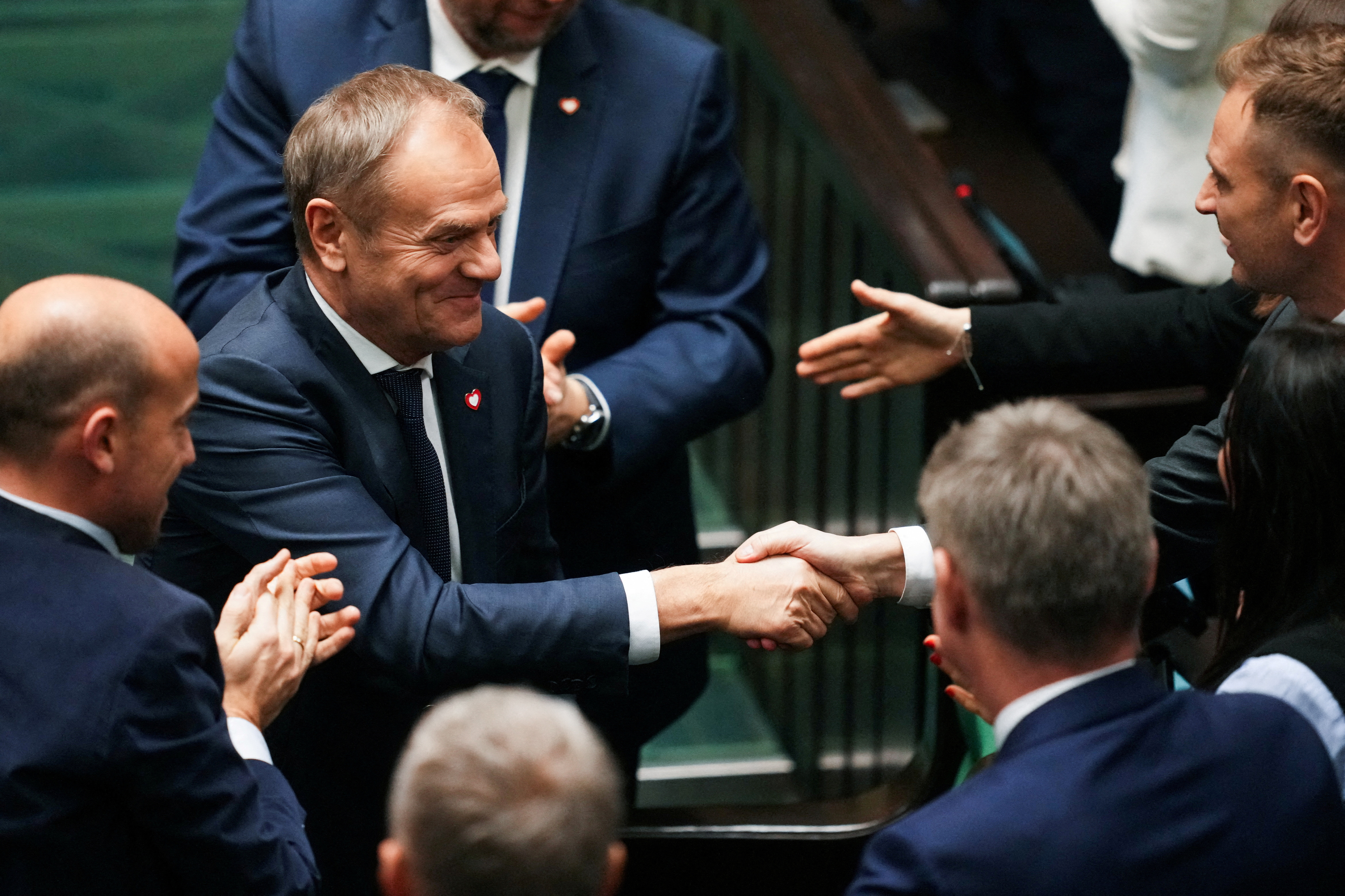 Members of the Polish Parliament congratulate newly appointed Polish Prime Minister Donald Tusk after he won the vote of confidence for his government, in Parliament, in Warsaw