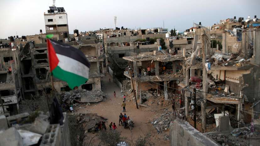 A Palestinian flag flies as the ruins of houses, which were destroyed by Israeli air strikes during the Israeli-Palestinian fighting, are seen, in Gaza