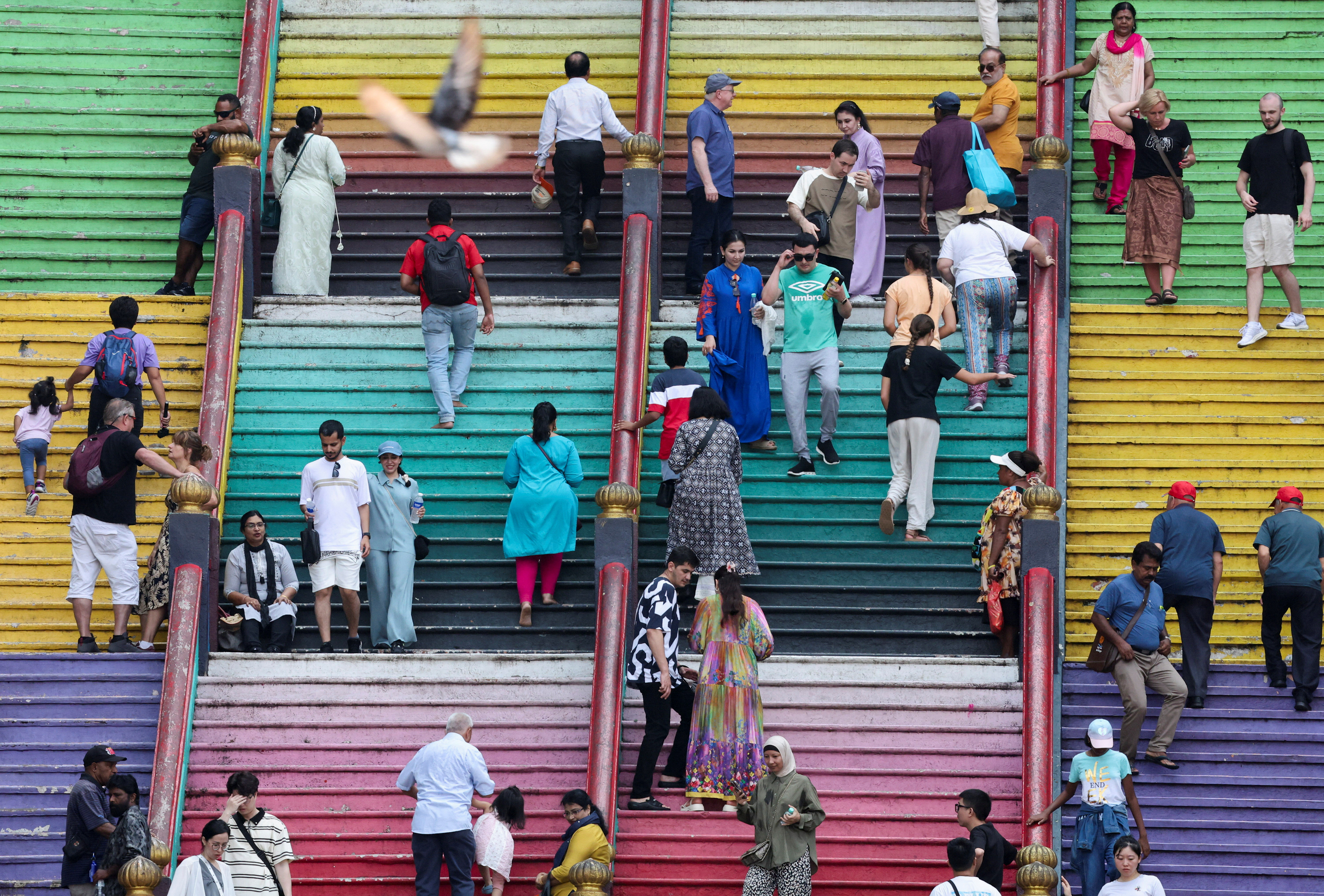 Tourists and Hindu devotees are seen on the 272 steps of Sri Subramaniar Swamy Temple at Batu Caves