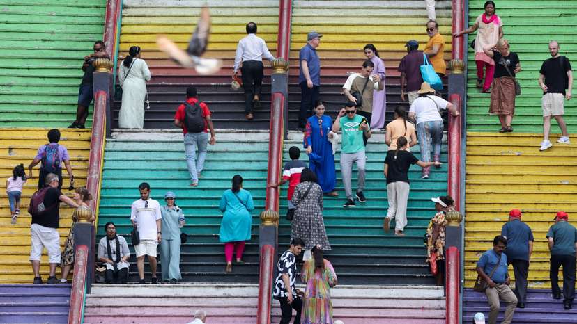 Tourists and Hindu devotees are seen on the 272 steps of Sri Subramaniar Swamy Temple at Batu Caves
