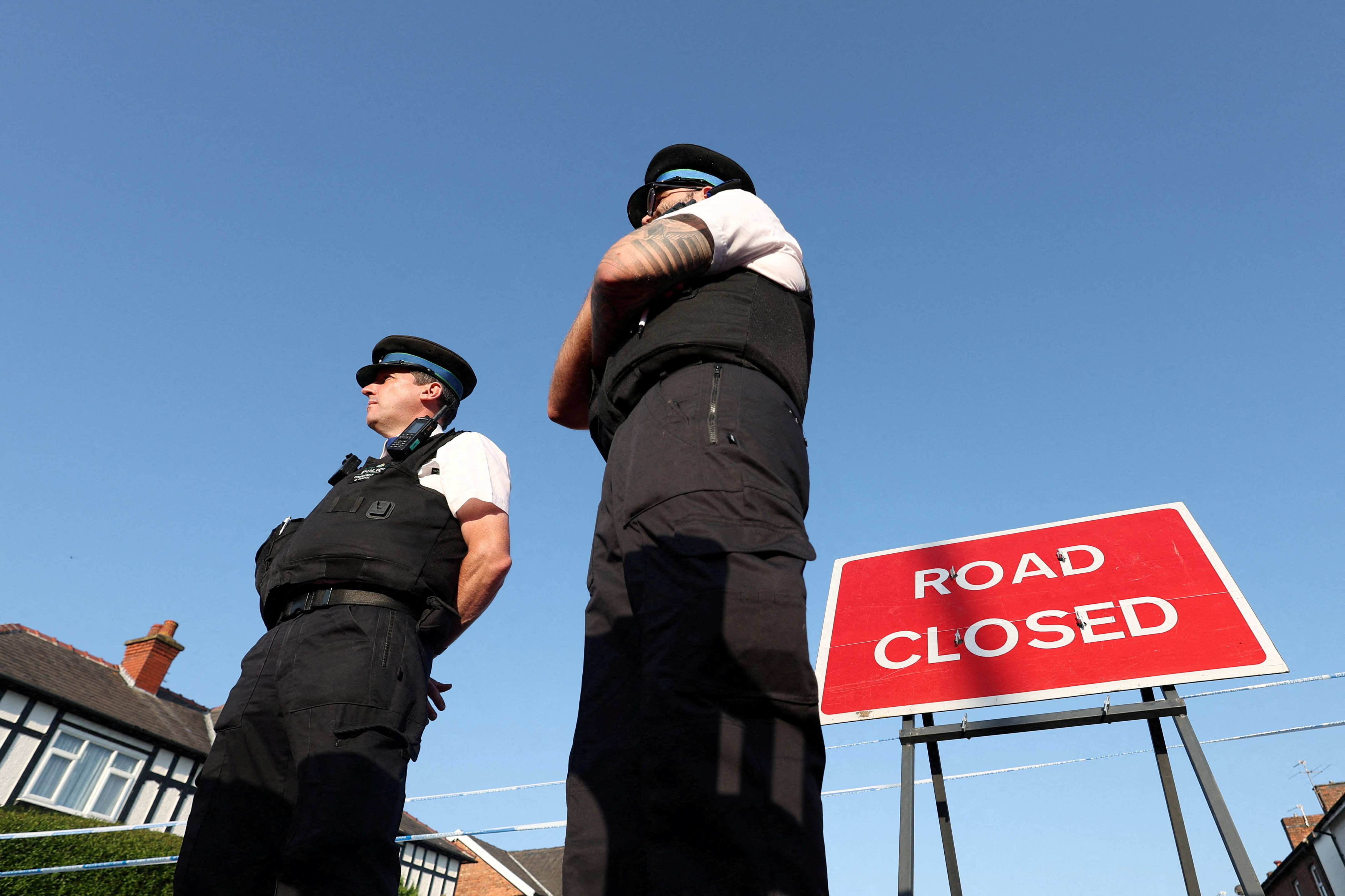 FILE PHOTO: Police officers stand near a "Road closed" sign, on the junction of Tithebarn Road and Hart Street, near the scene where a teenage suspect was arrested after people were stabbed in Southport