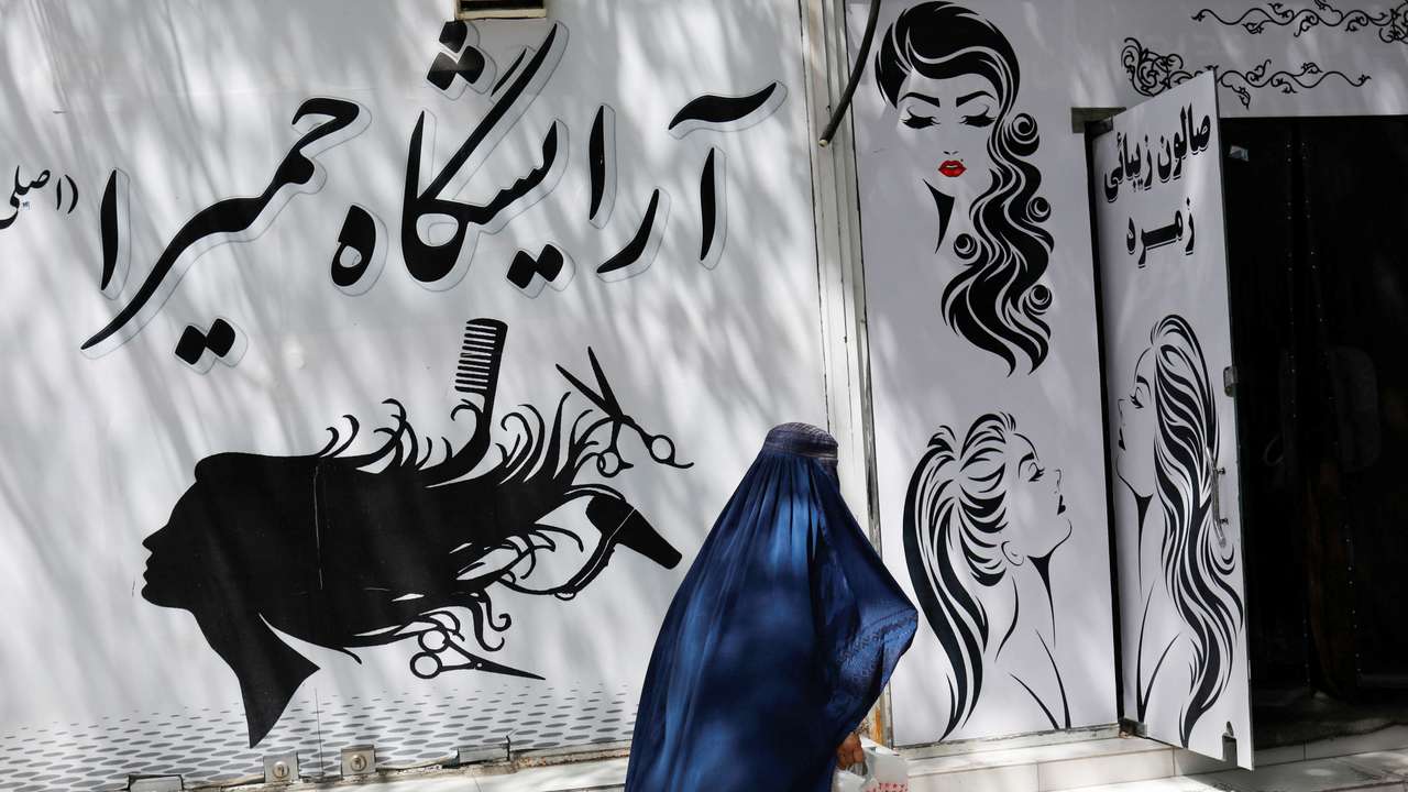 An Afghan woman walks past a beauty salon in Kabul