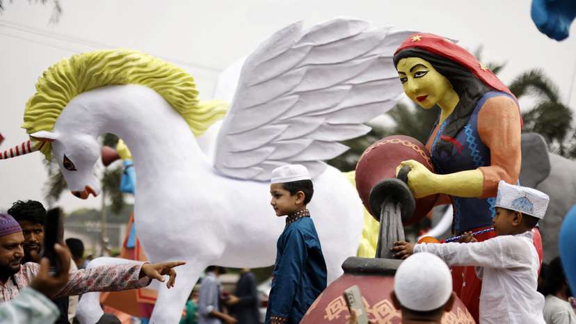 Children take pictures with makeshift sculptures brought to an Eid al-Fitr rally to mark the end of the holy month of Ramadan, in Dhaka