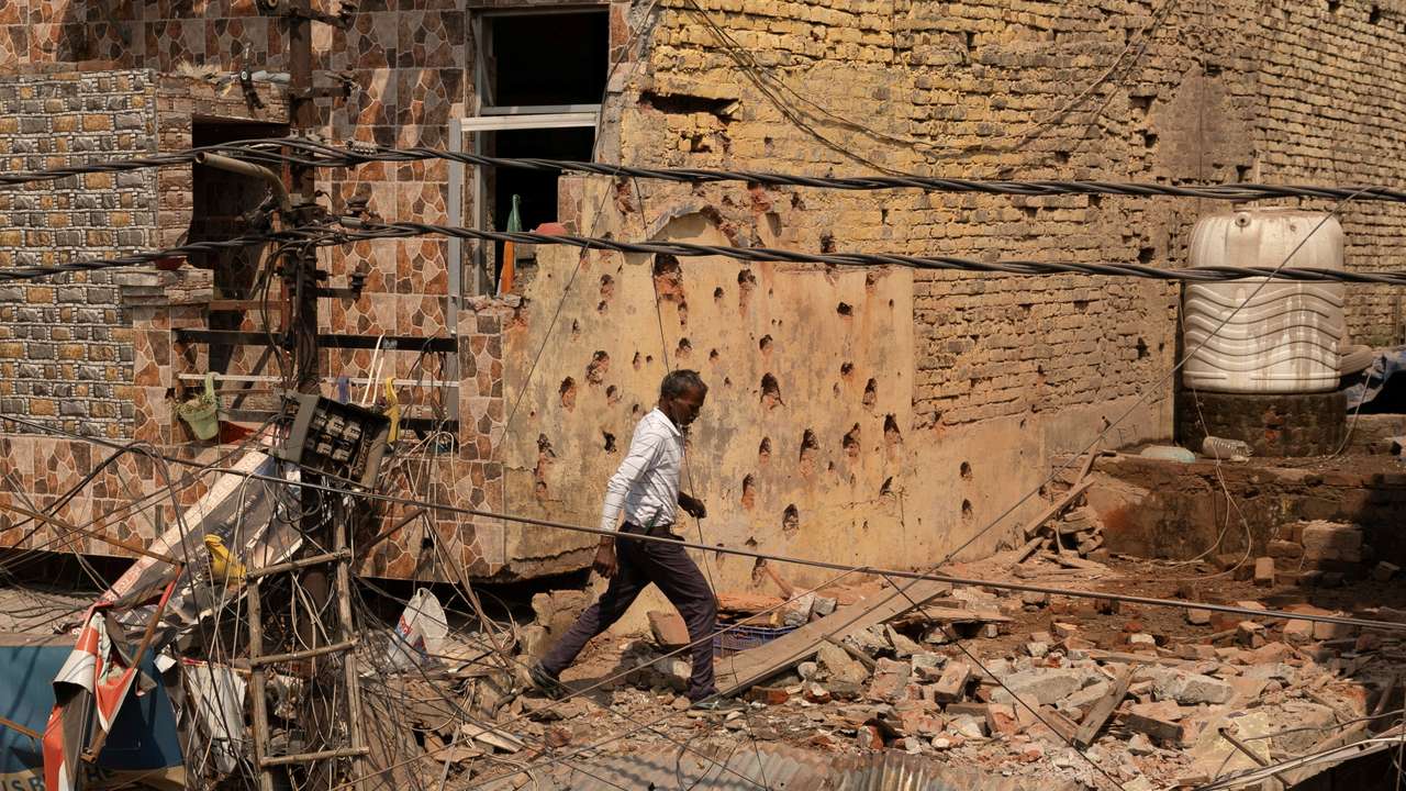 A man walks amidst debris on the roof of a damaged house, following Pakistan's military operation against India, in Rehari, Jammu