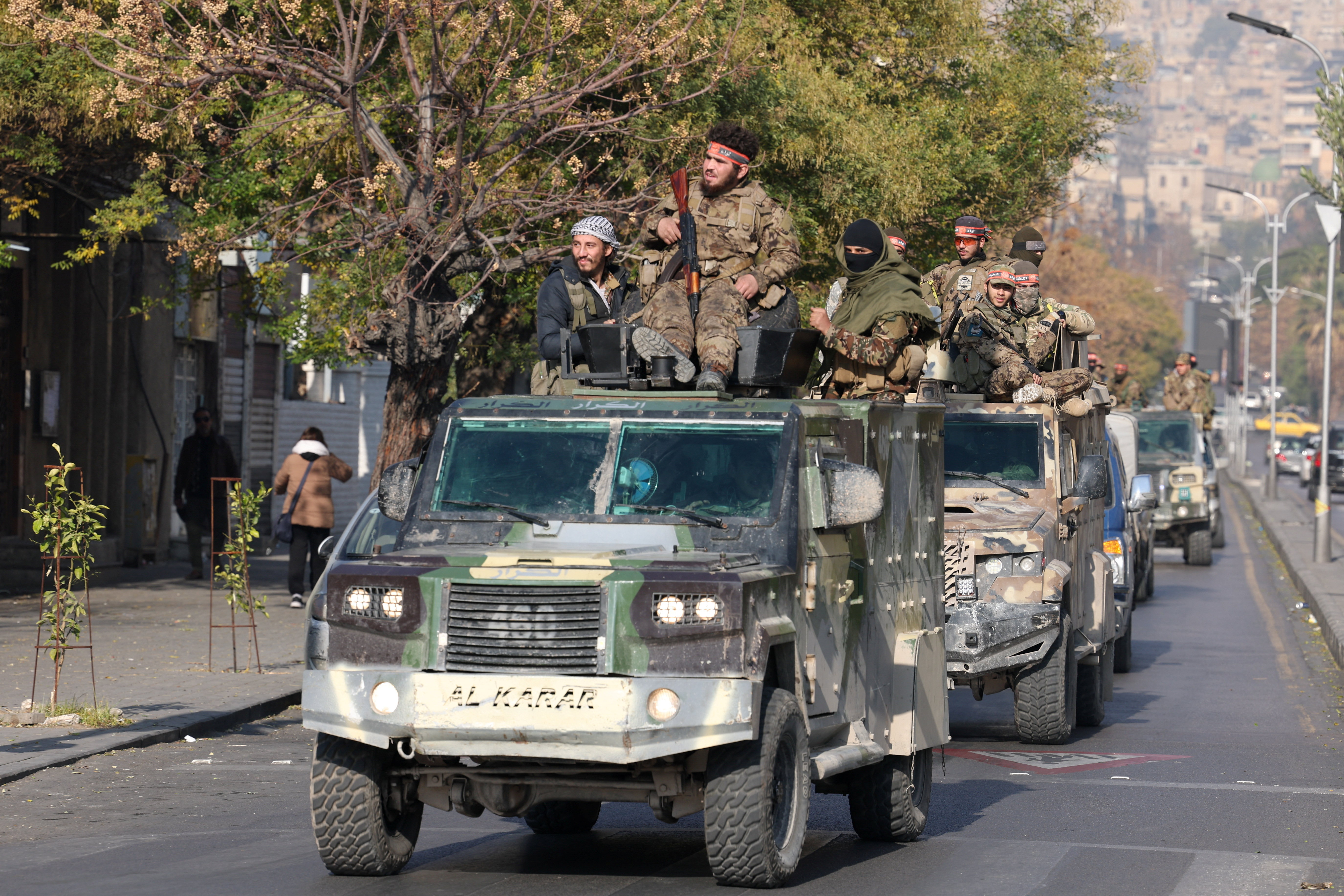 Rebel fighters ride on vehicles, in Damascus