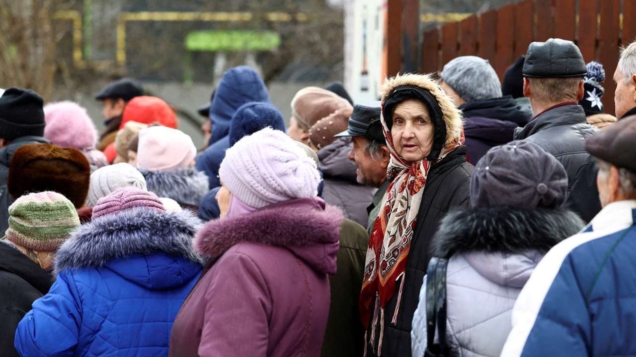FILE PHOTO: People queue for a meal distribution in Kherson