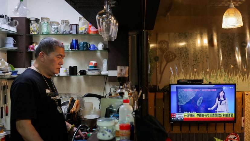 FILE PHOTO: A person stands in a cafe as a news broadcast shows China announcing new military drills around Taiwan, in Keelung