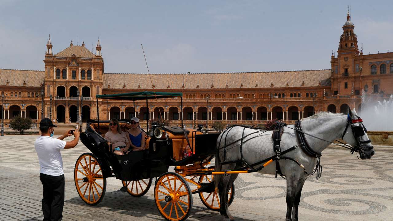 FILE PHOTO: A coachman takes a picture of tourists as they sit on a horse-drawn carriage at the Plaza de Espana, as a heatwave hits Spain, in Seville
