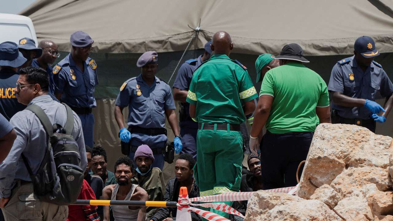 Rescued miners are seen as they are processed by police after being rescued at the mine shaft, in Stilfontein