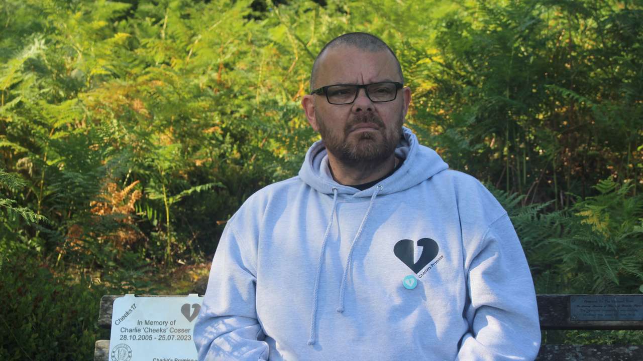Martin Cosser sits on a memorial bench with a plaque honouring his son Charlie, at Devil's Punch Bowl, in Surrey