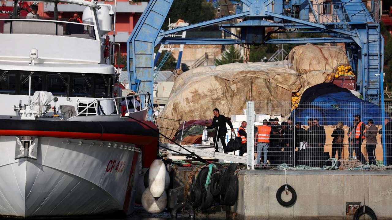 FILE PHOTO: Migrants board an Italian coast guard vessel in Shengjin, Albania