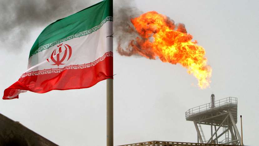 FILE PHOTO: A gas flare on an oil production platform is seen alongside an Iranian flag in the Gulf