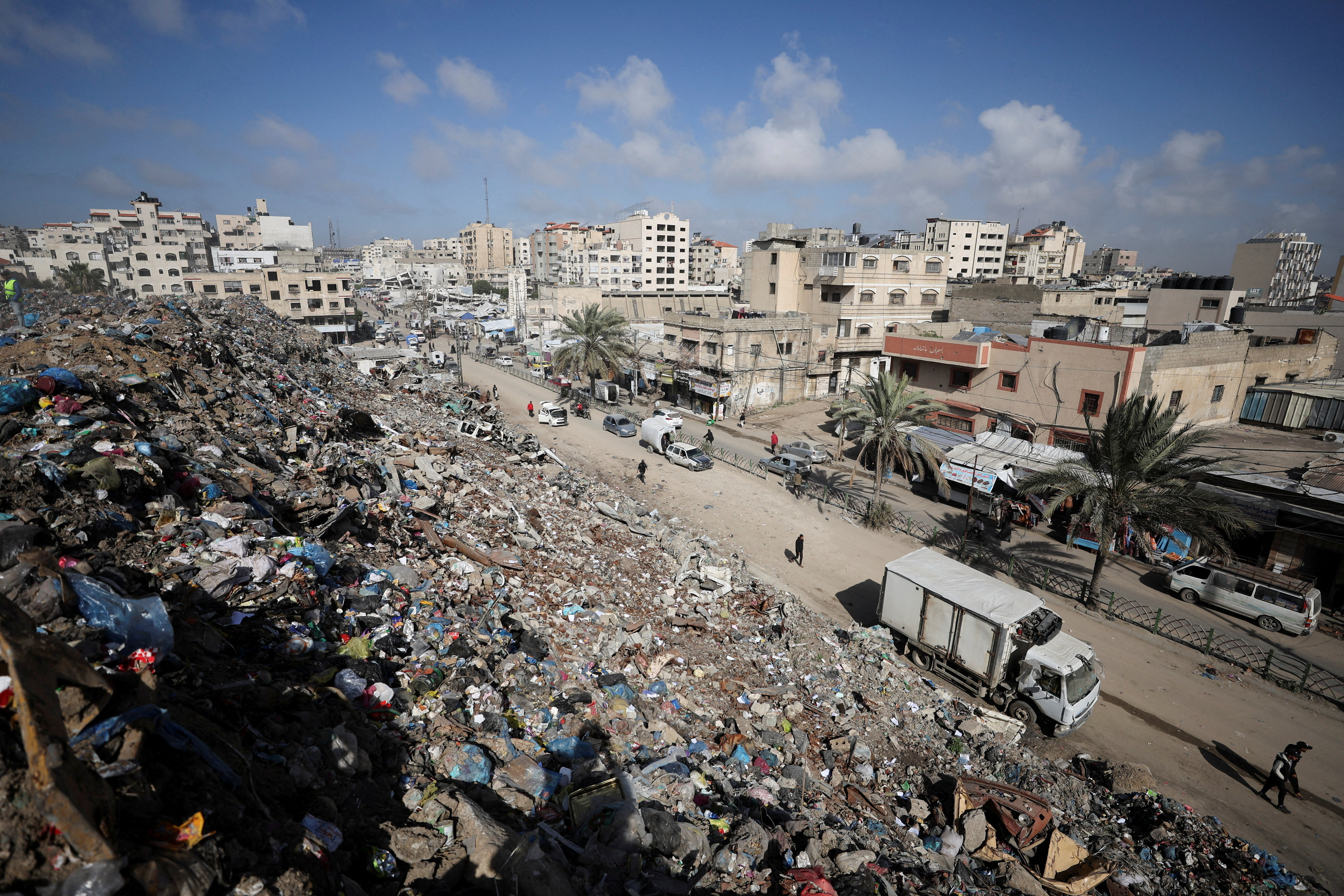 Palestinians walk near a landfill, in Gaza