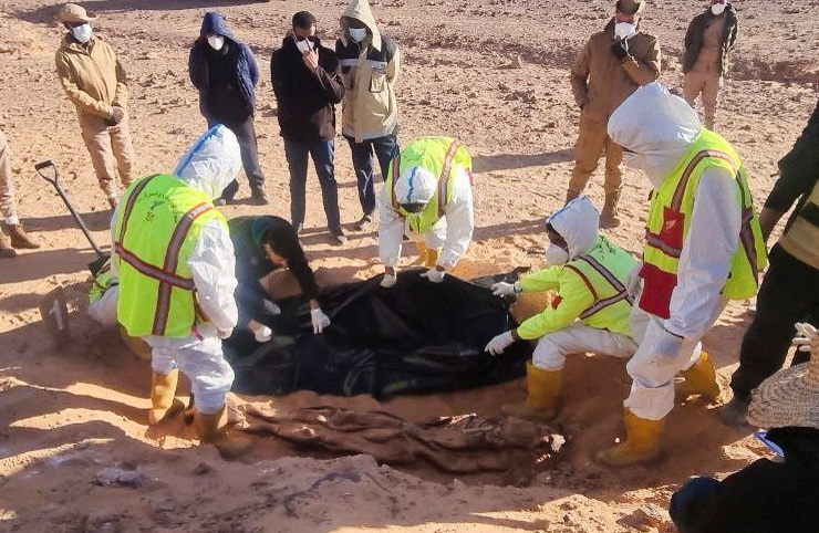 Members of the ambulance and emergency services and security forces recover the bodies of migrants after they were discovered in a mass grave north of Kufra city