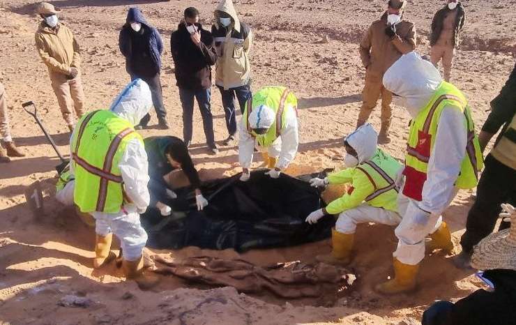 Members of the ambulance and emergency services and security forces recover the bodies of migrants after they were discovered in a mass grave north of Kufra city