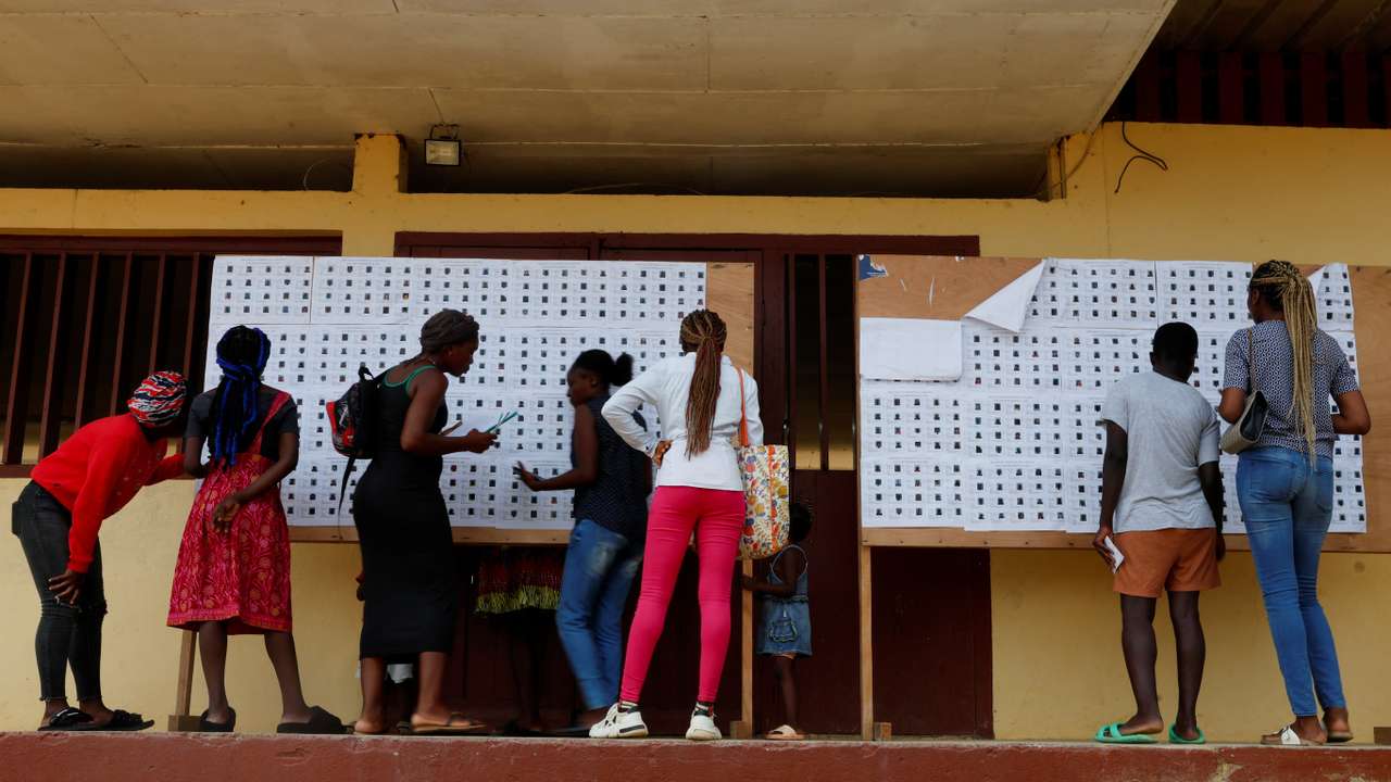 People look for their name on the electoral roll, ahead of the 2025 Gabonese presidential electionat a polling station in Lambarene